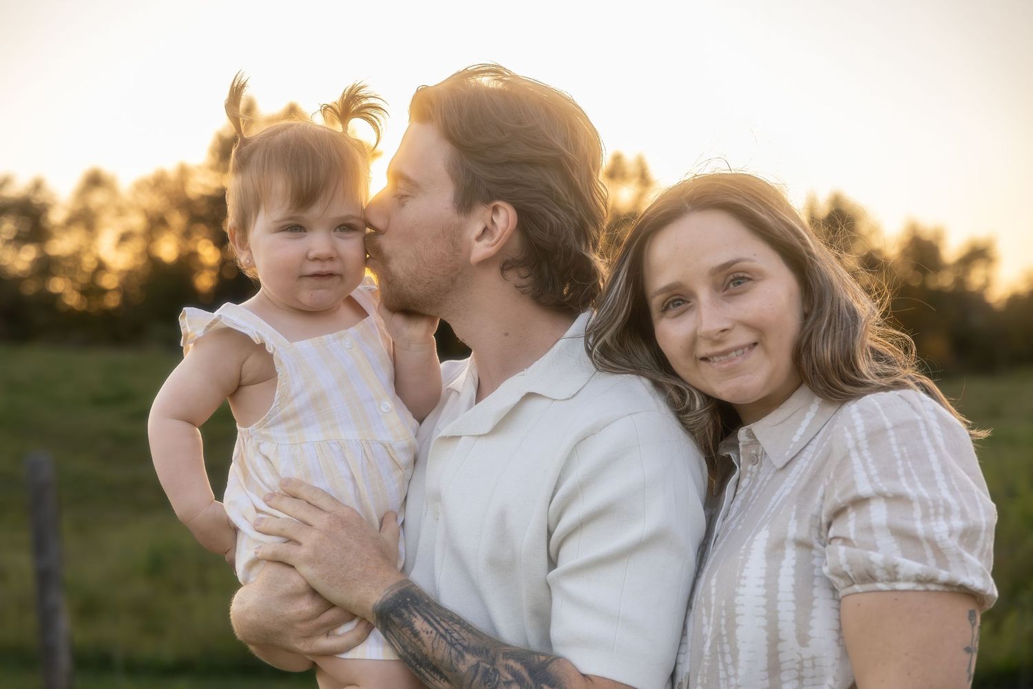 Joyful family portrait session captured during sunset in a natural outdoor setting.
