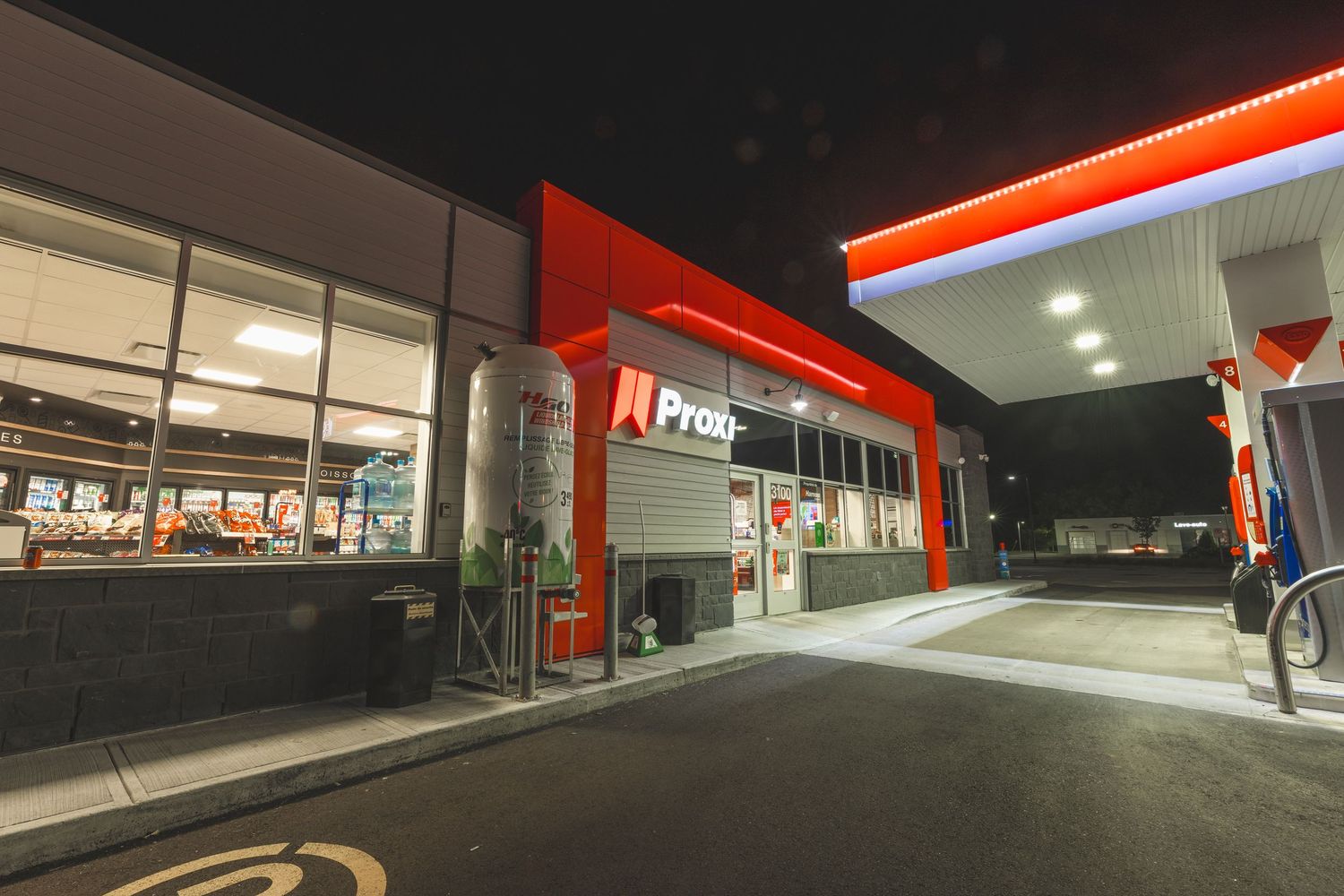Empty parking lot at night with red illuminated storefront and glowing signage creating an atmospheric scene.
