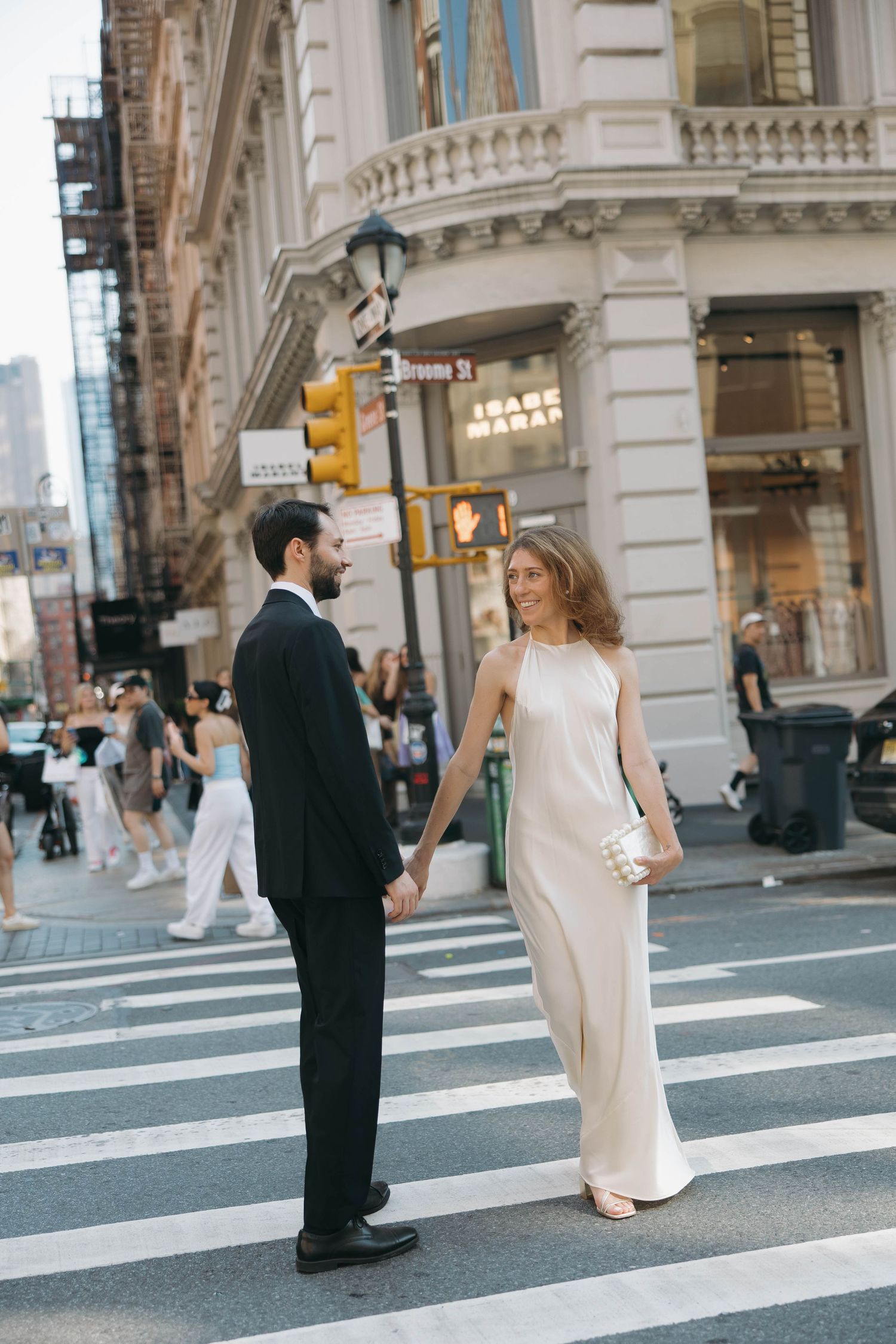 Couple walking across a city crosswalk in formal attire.