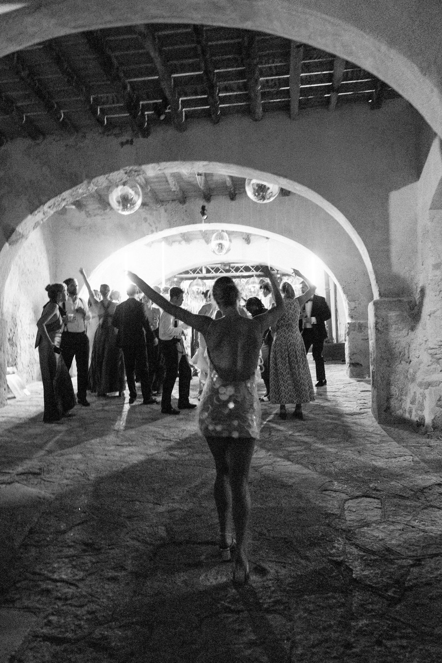 People gathering in a historic vaulted stone cellar with arched ceilings and ambient lighting.