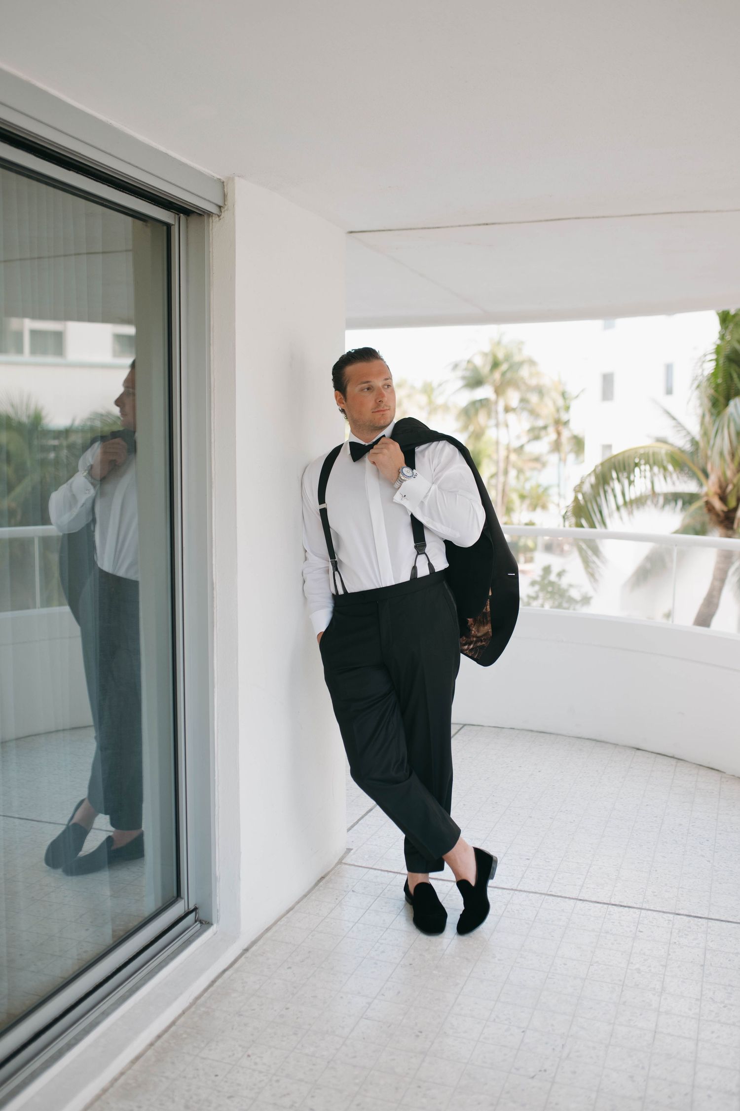 Person in formal black and white attire playfully posing against a white wall in a series of dynamic shots.