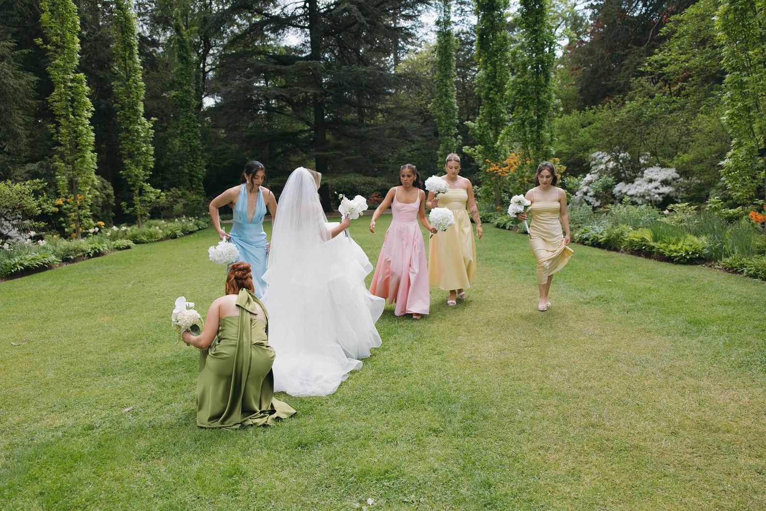 Wedding party walking and laughing together on a lush green lawn.