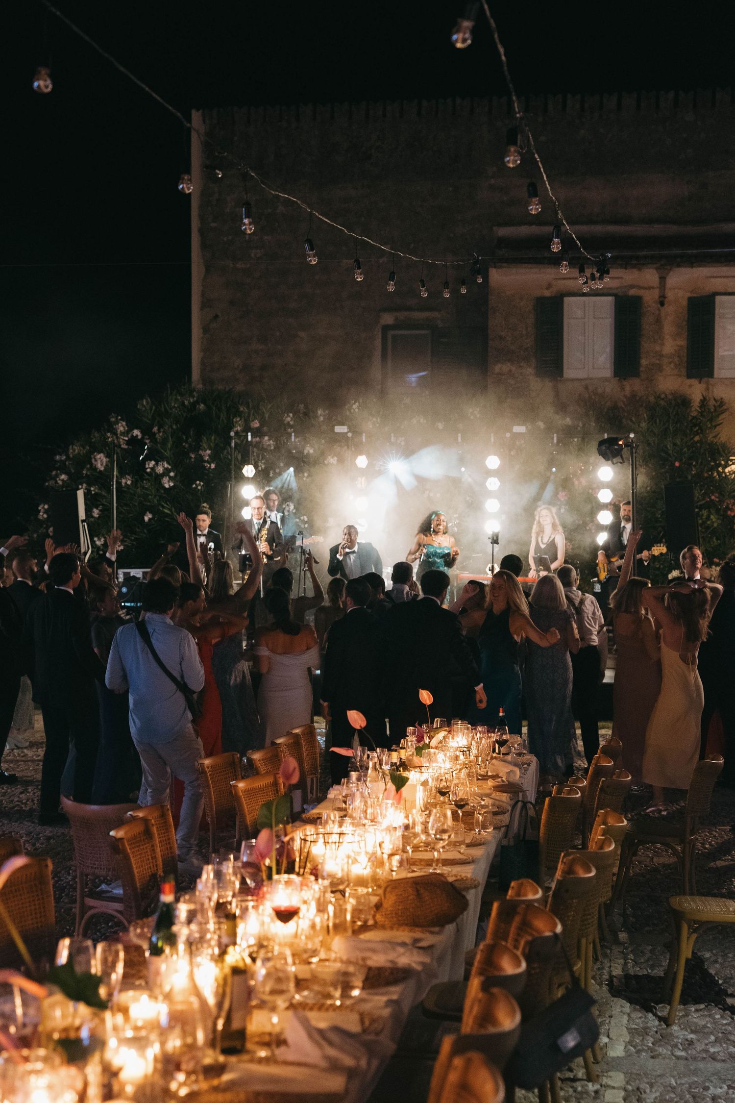 Candlelit wedding reception tables creating a romantic ambiance in a rustic venue.