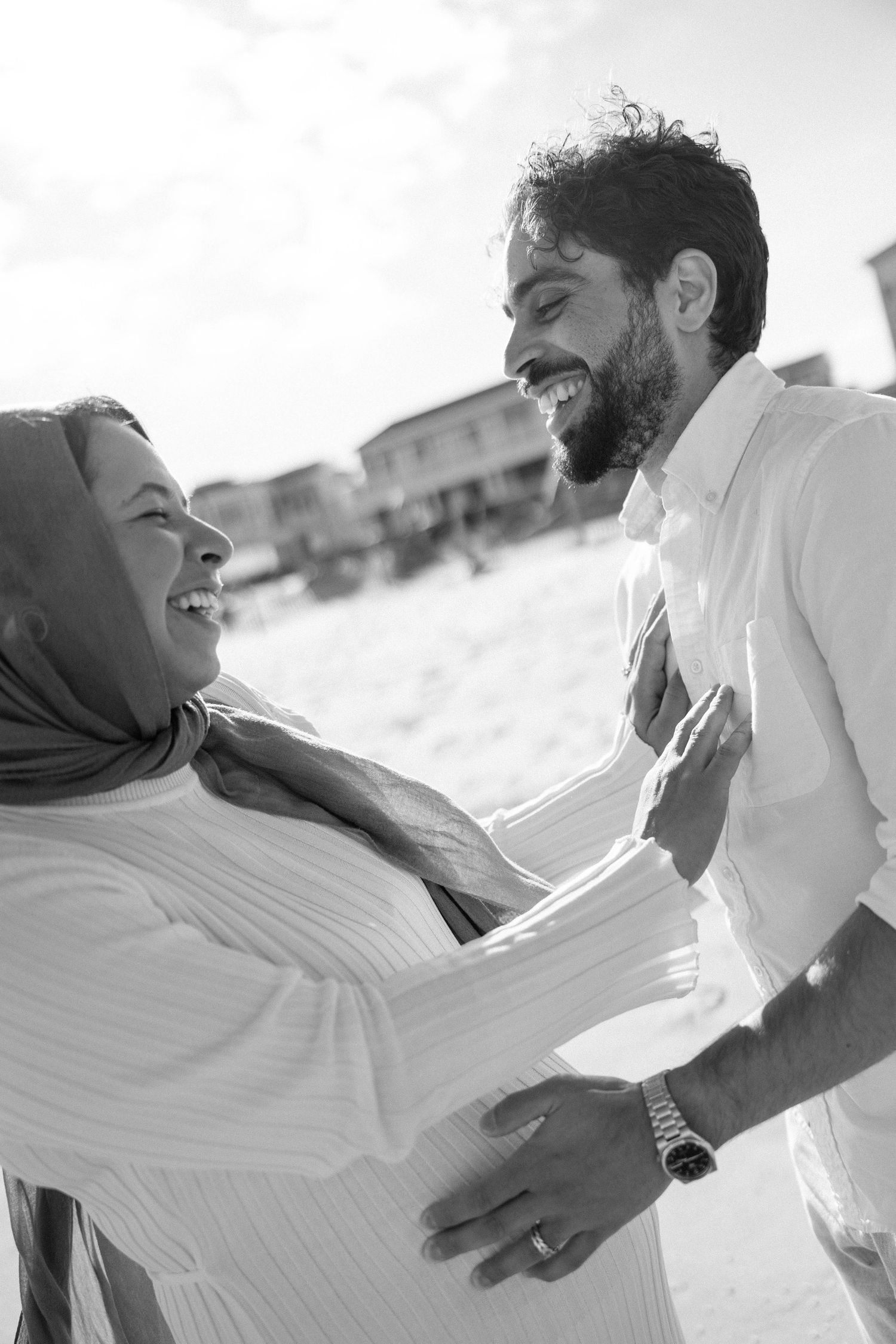 Black and white sequence showing playful interaction between two people in white clothing at the beach.