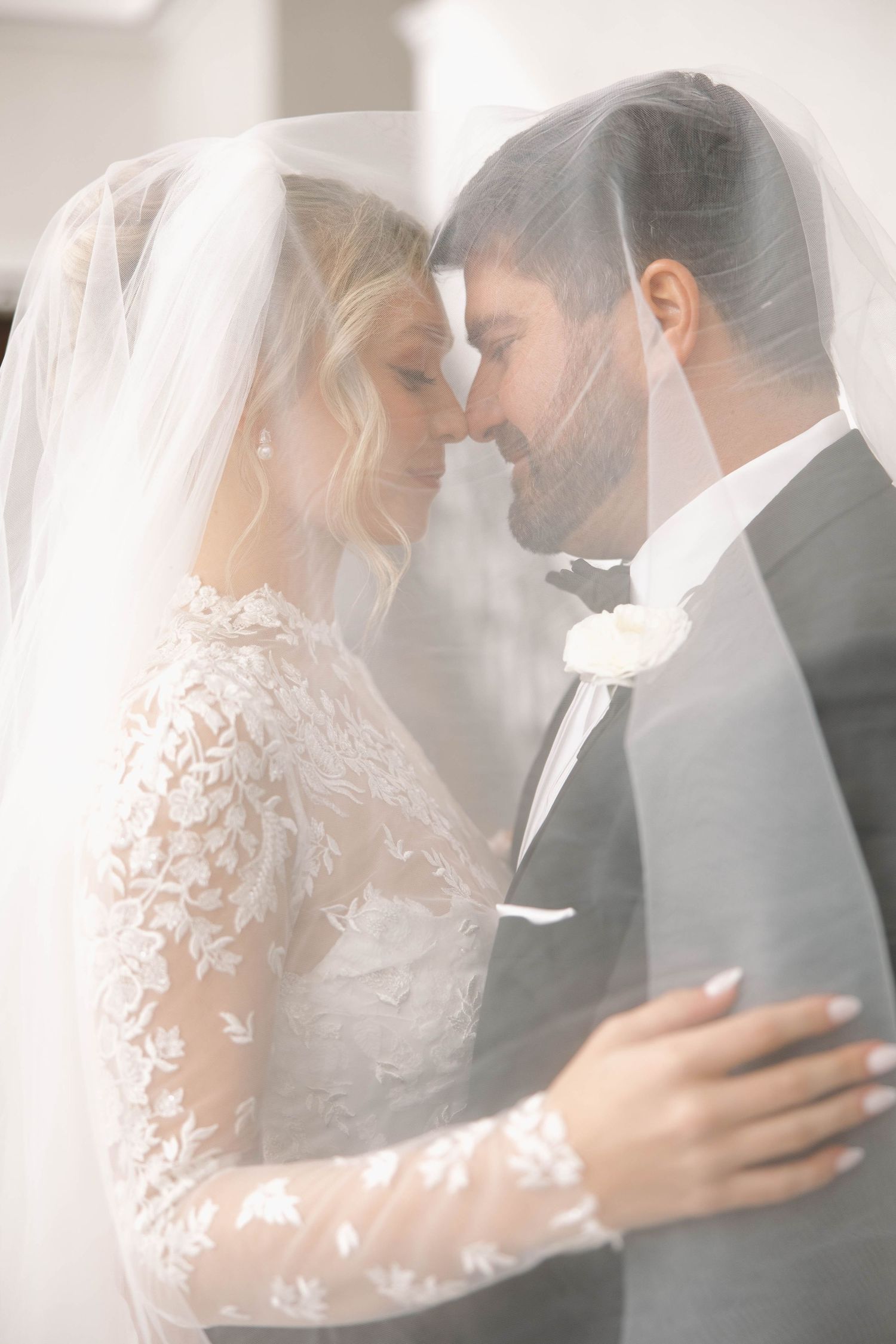 Ethereal wedding photos showing intimate moments between couple beneath lace veil.