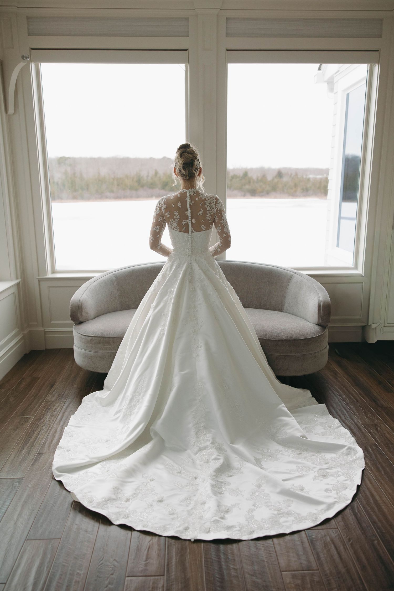 Full length wedding gown with dramatic train against window backdrop.