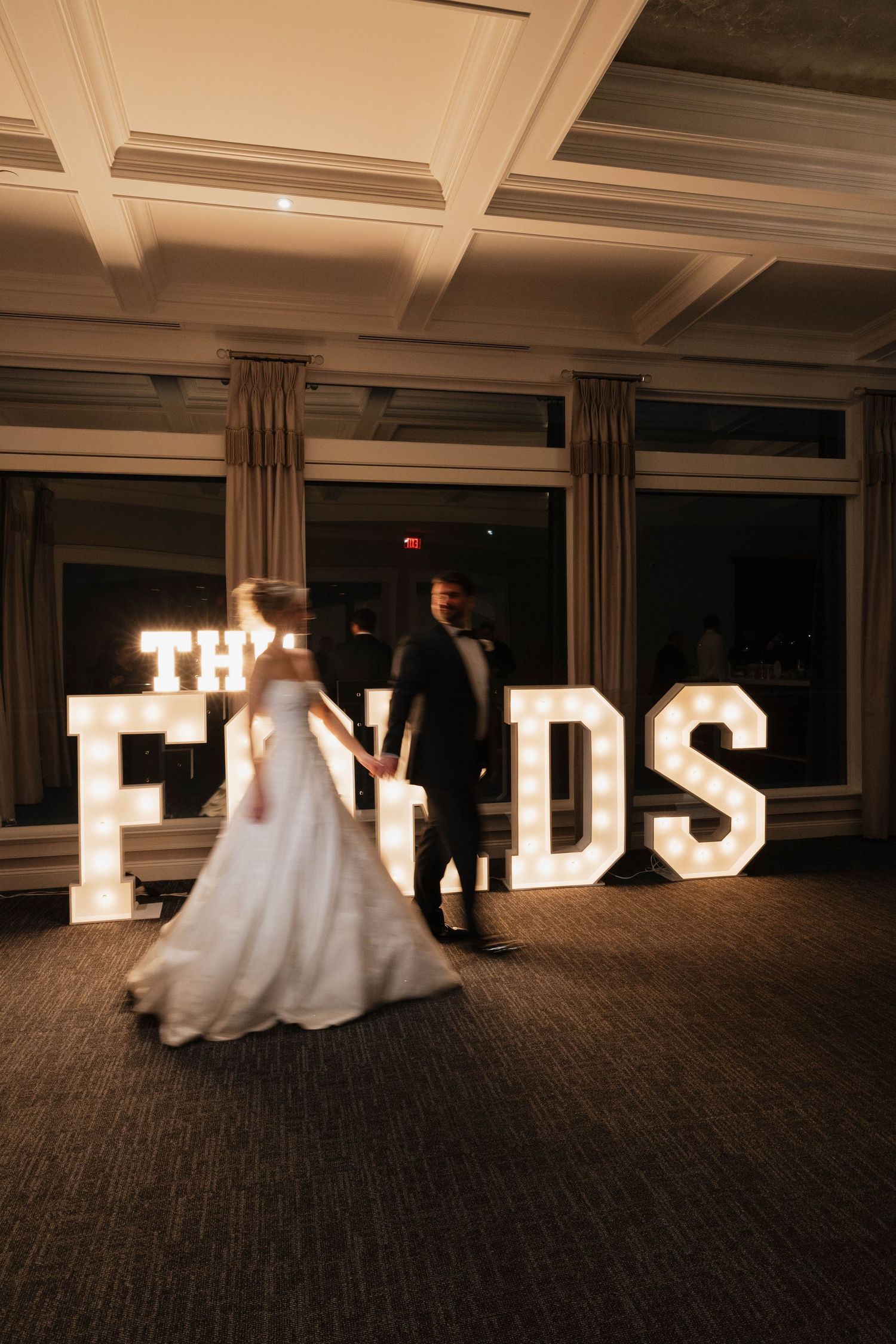 Illuminated marquee letters spelling out words against dark background at wedding reception.