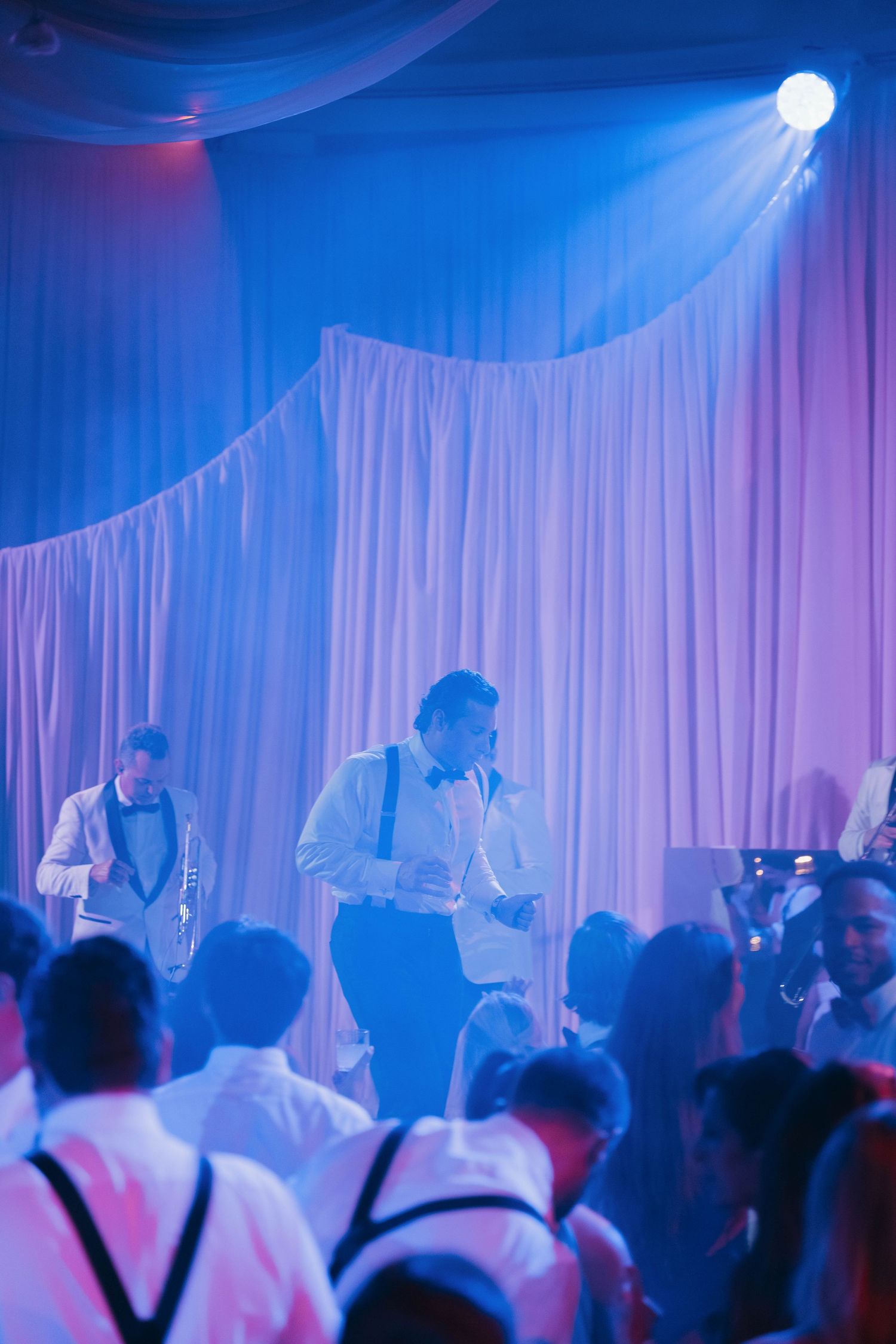 Dance party with dramatic blue lighting and white drapes creating an atmospheric nightclub setting.