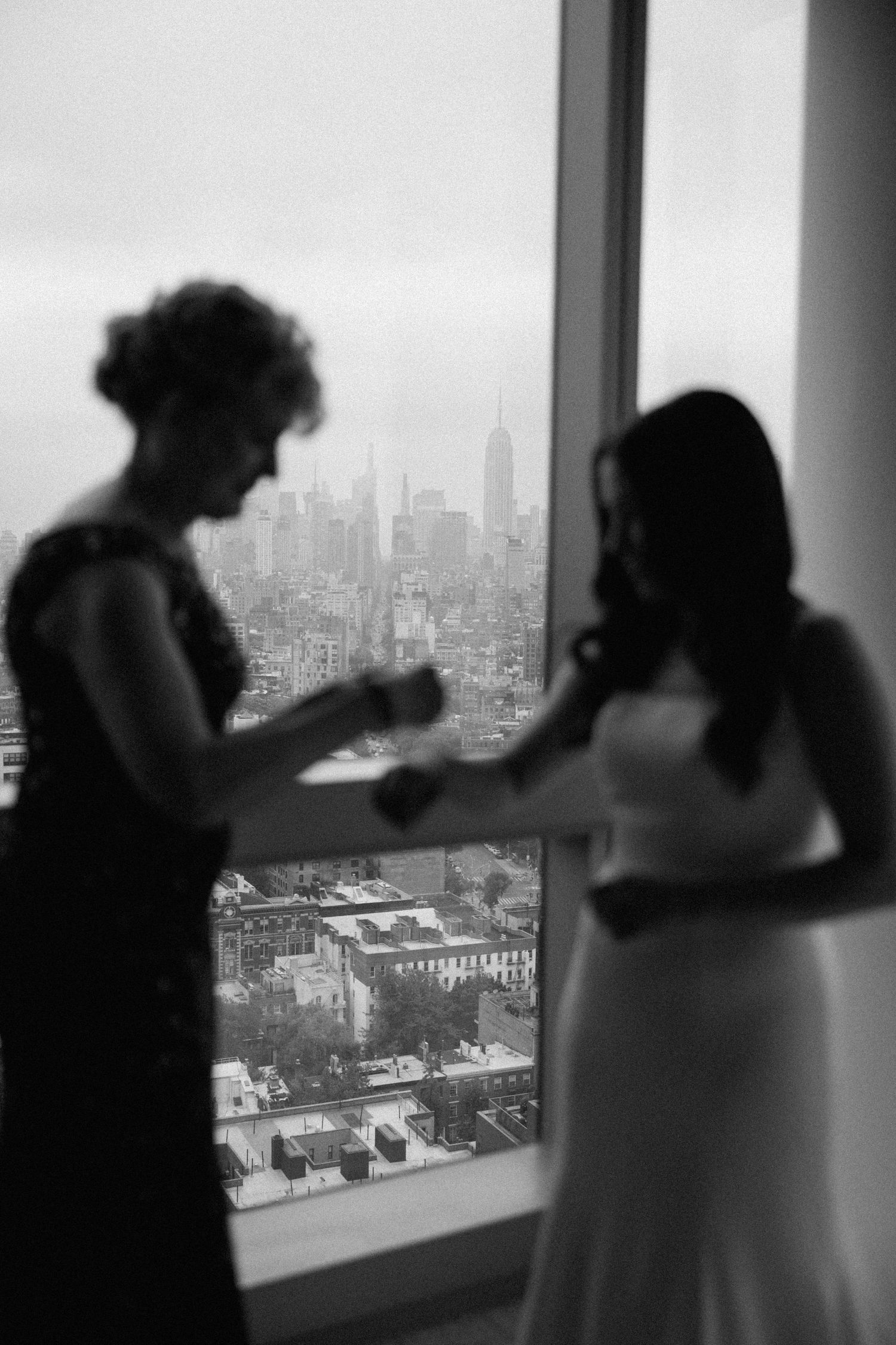 Silhouettes of people gathered by windows overlooking a dramatic city skyline.