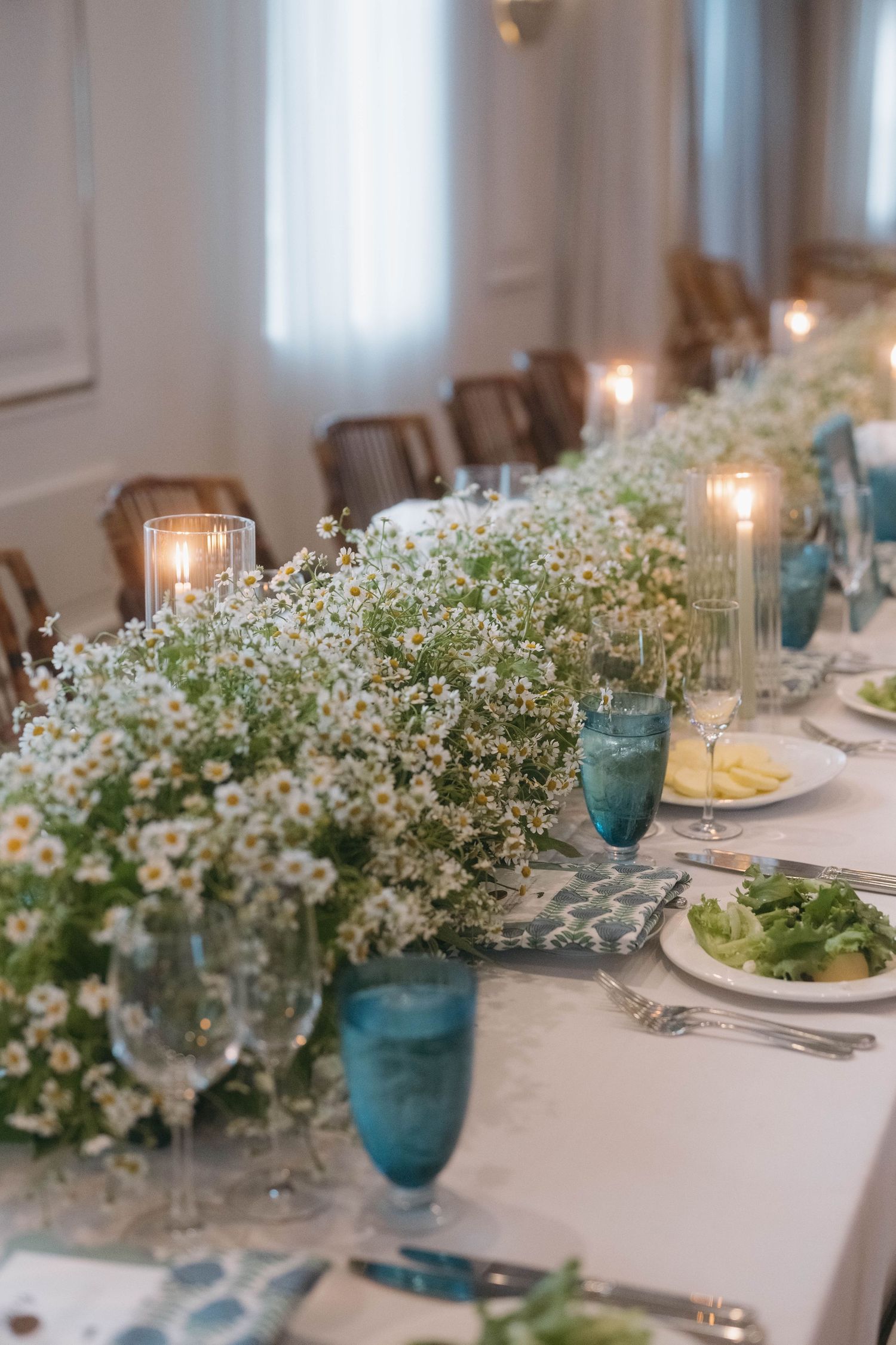 Elegant wedding table setting with white baby's breath centerpieces and blue glassware on crisp white linens.
