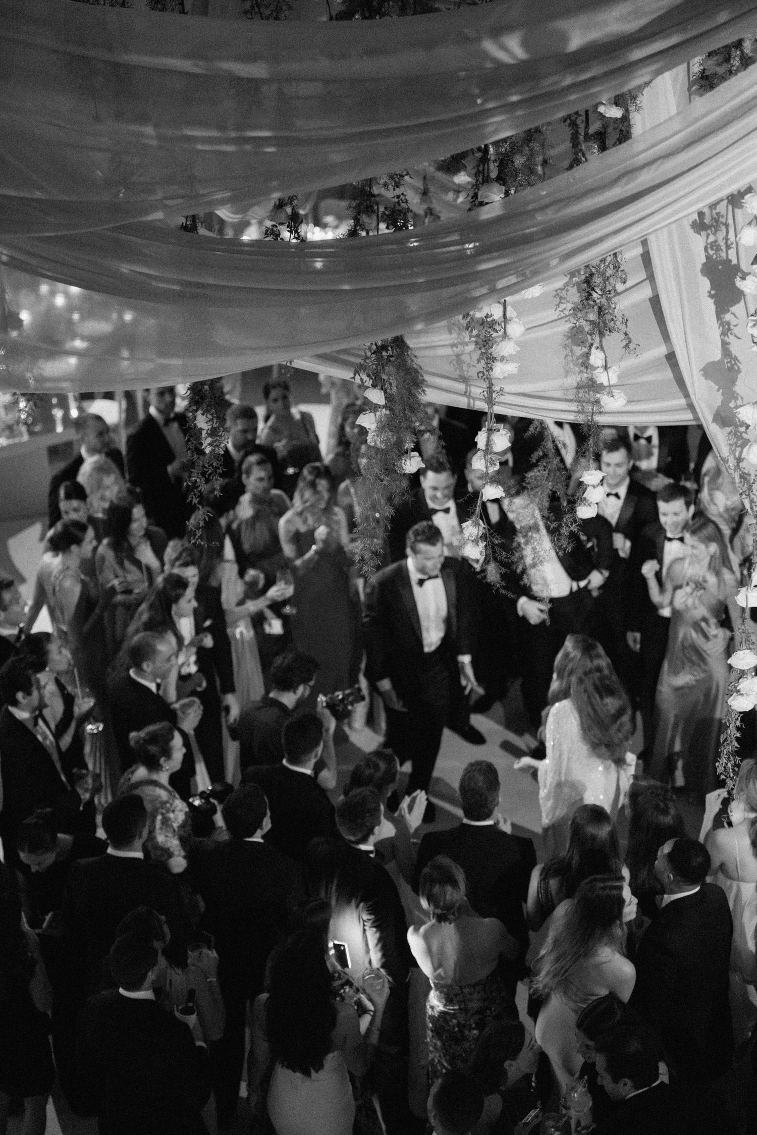 Wedding guests dancing and socializing at an elegant black-tie reception.