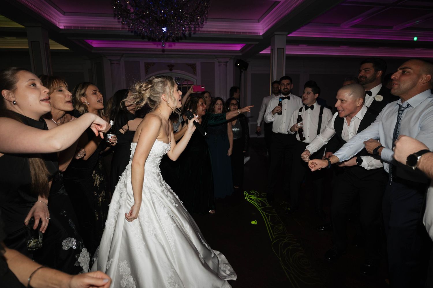 Formal event dance floor with purple accent lighting and celebrating guests.
