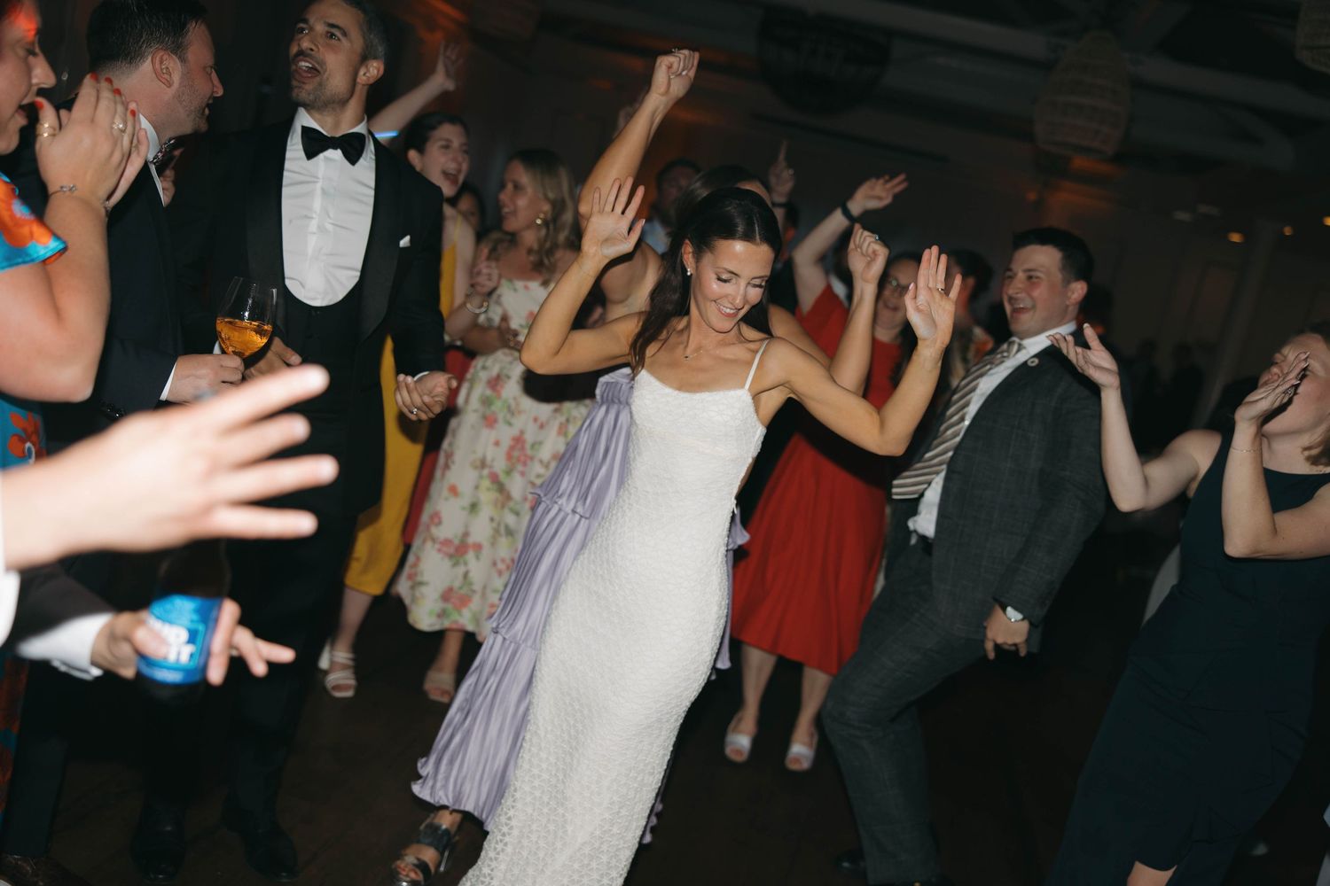 Party guests dancing and celebrating at a formal event with dramatic lighting.