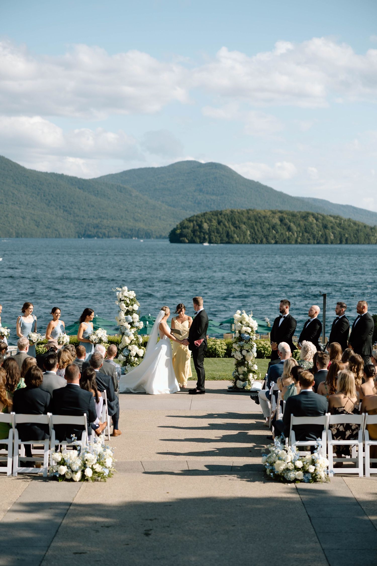 Lakeside wedding ceremony setup with mountain views and white chairs.