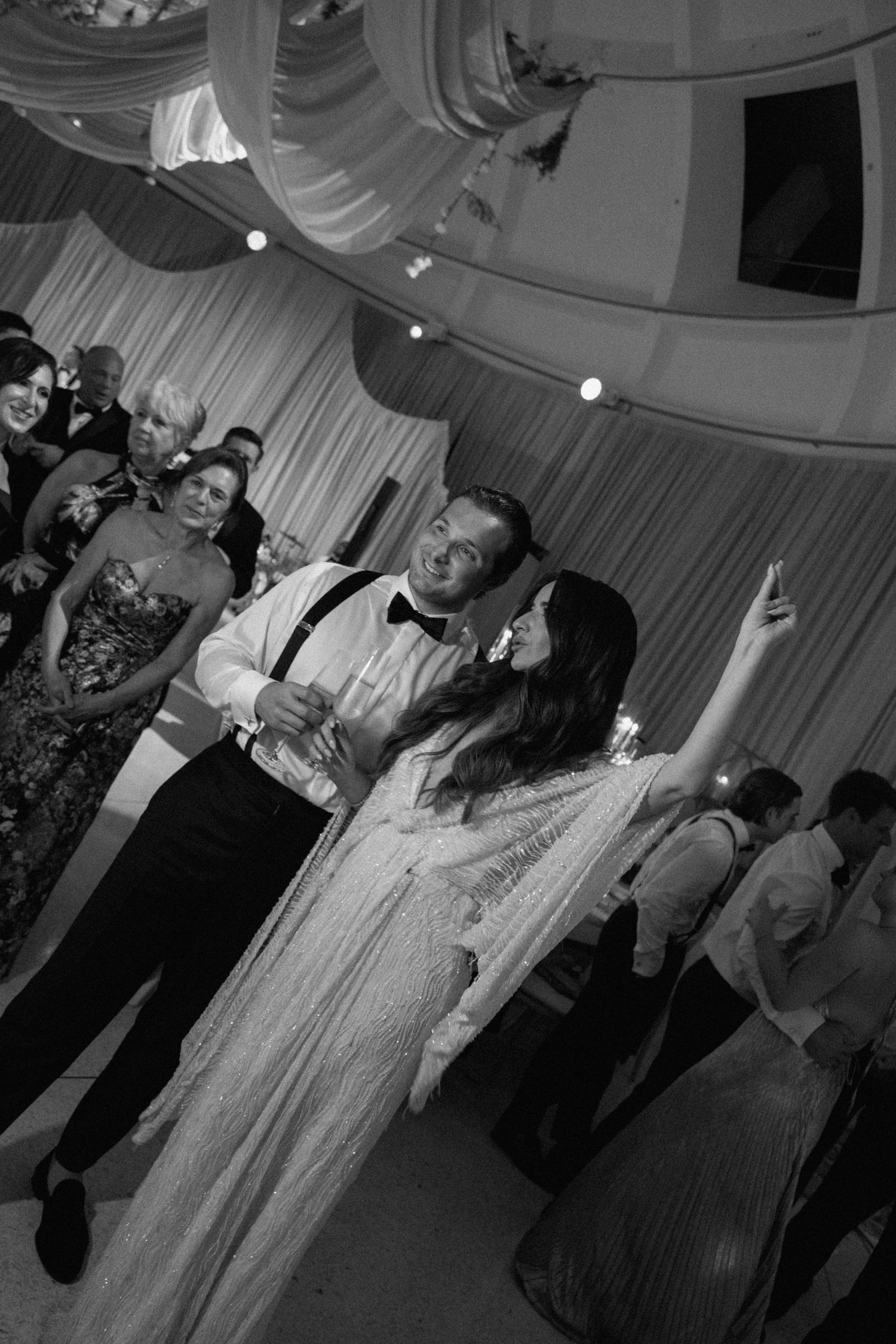 Wedding guests dancing and celebrating on the reception dance floor.