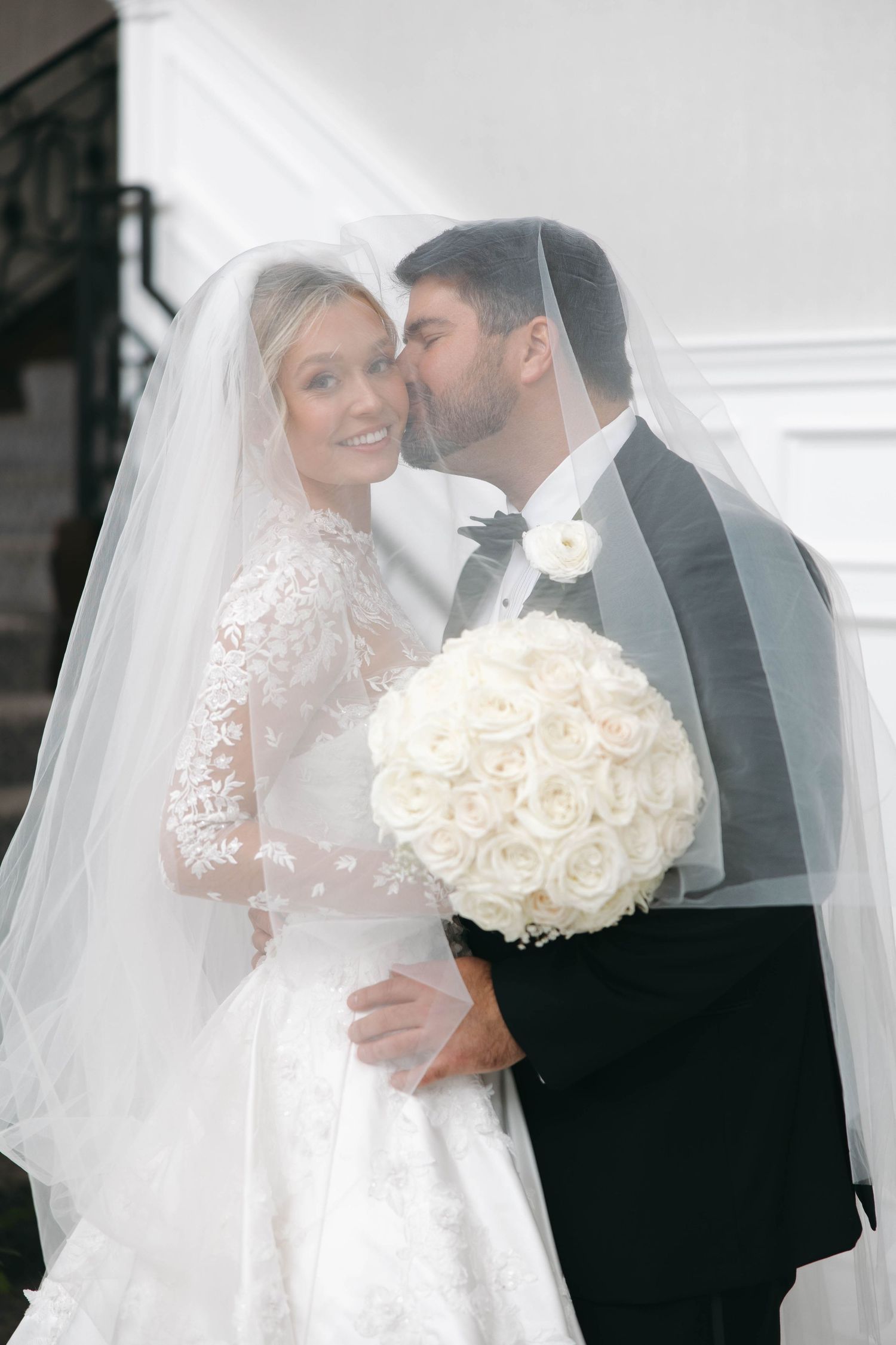 Romantic wedding portraits with white rose bouquet and flowing veil.