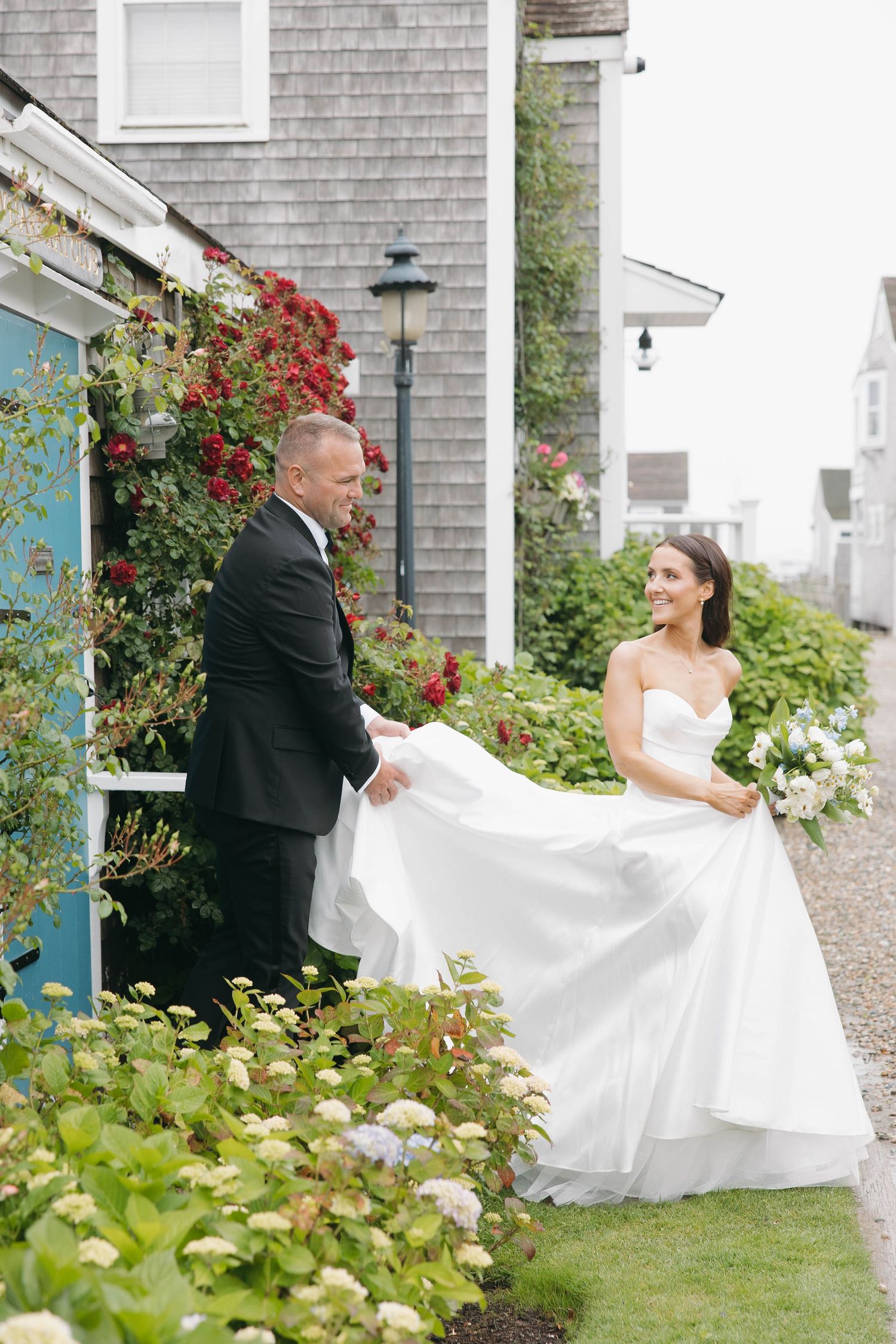 Joyful wedding sequence showing couple dancing and twirling on garden path by shingled house.