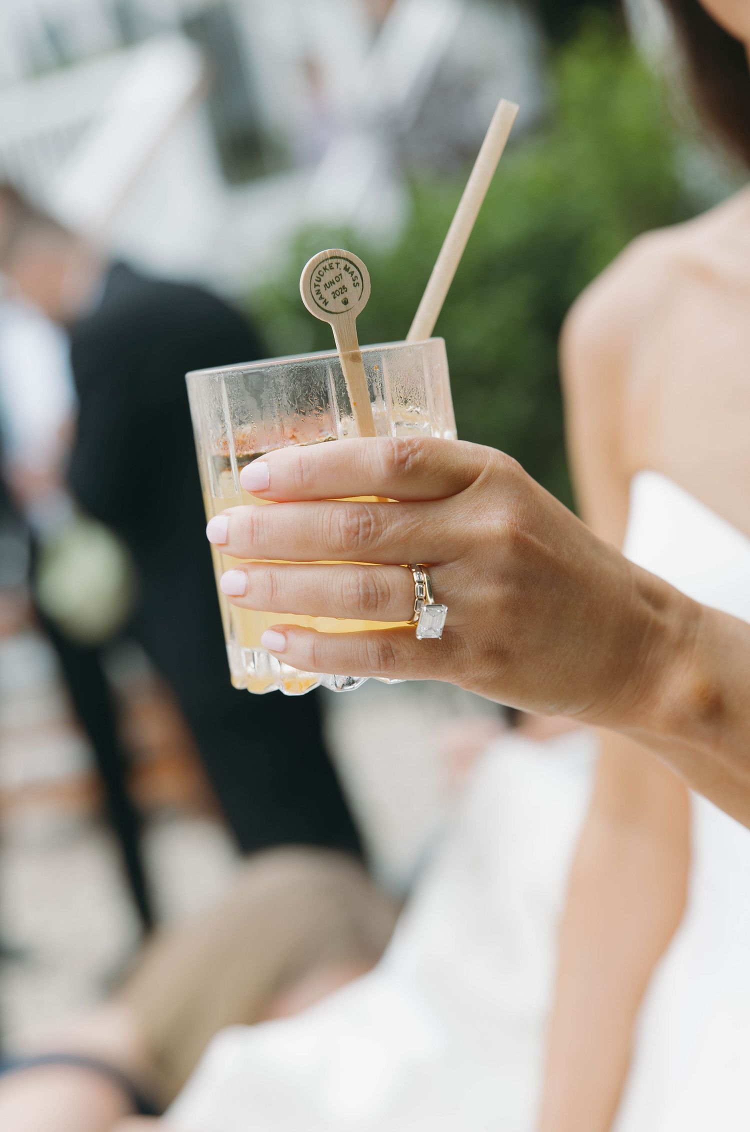 Hand holds cocktail with wooden stir stick at elegant wedding reception.