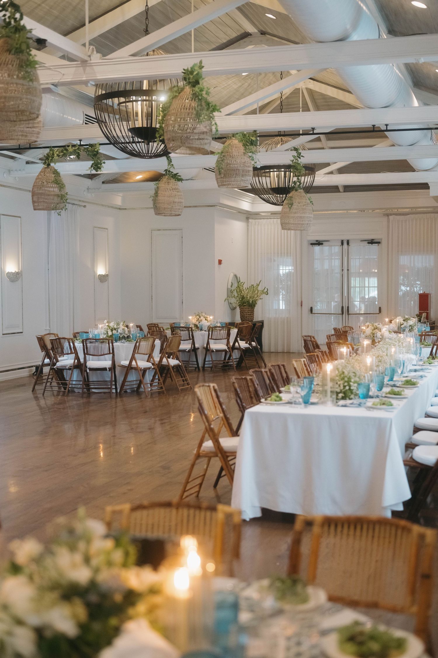 Rustic wedding venue with exposed beams, wooden chairs, and elegant table settings.