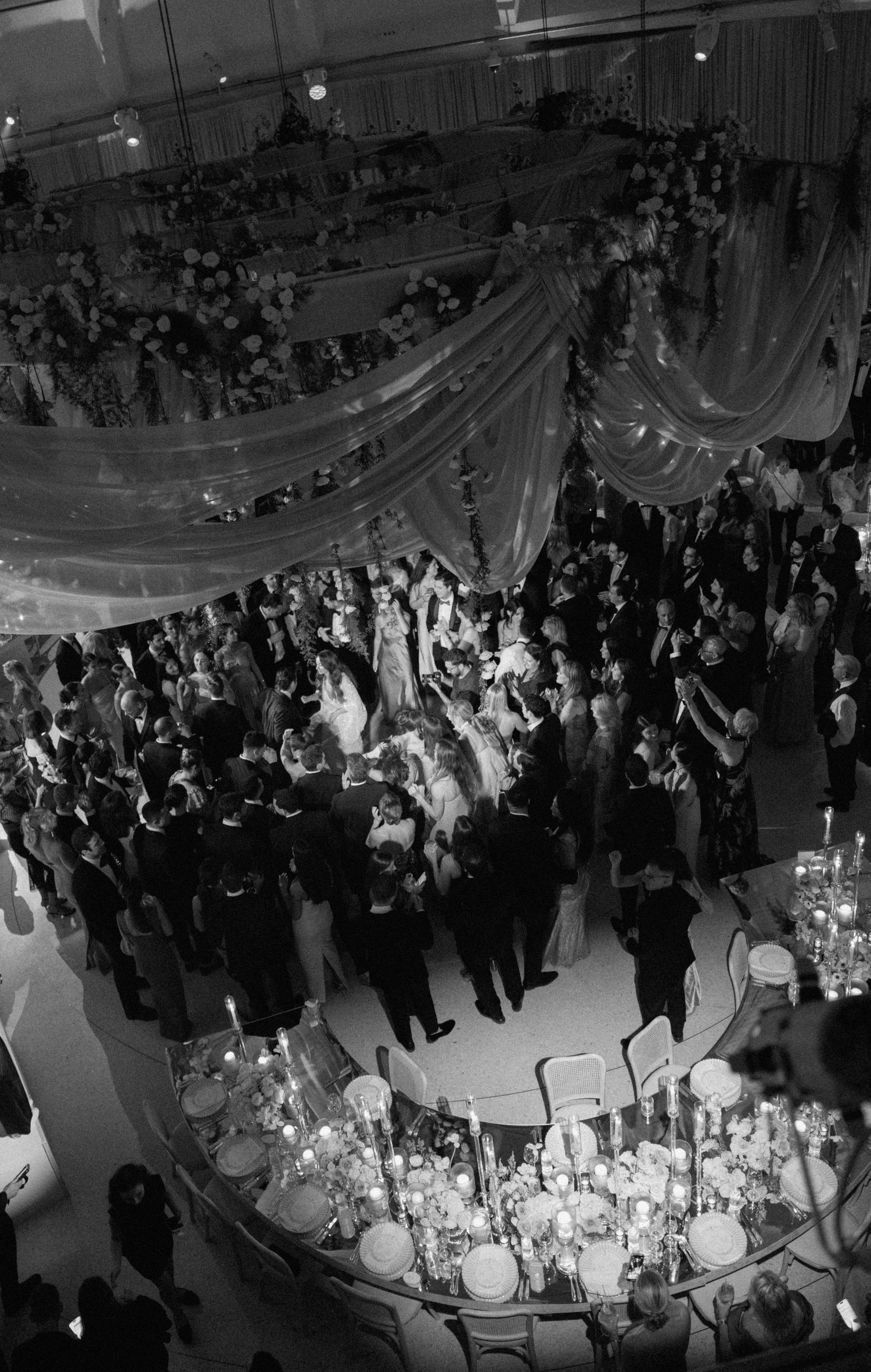 Aerial view of a wedding reception showing guests dancing under elegant draped ceiling decor.