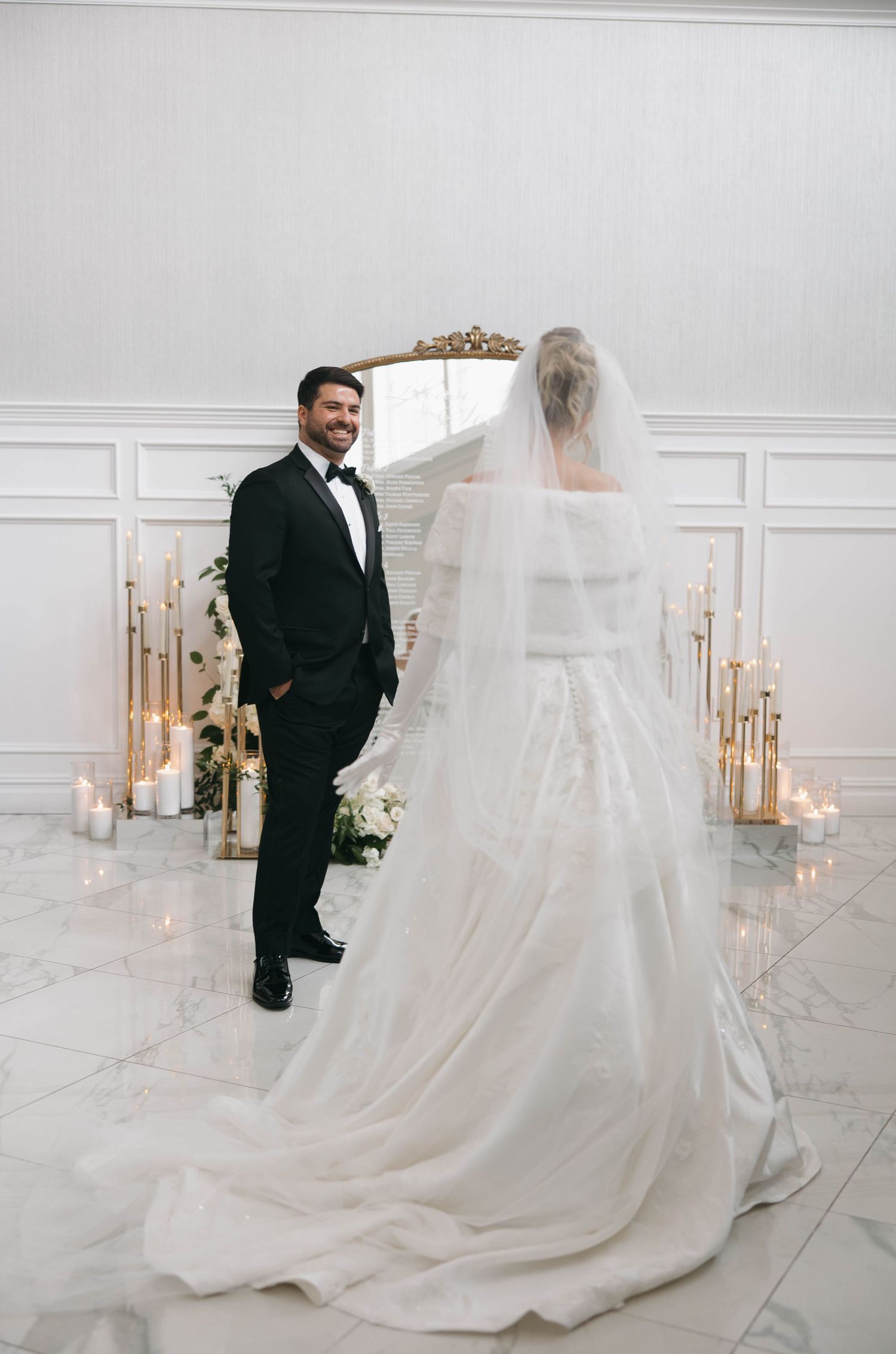 Dramatic wedding portrait in white room with candlelit details and flowing veil.
