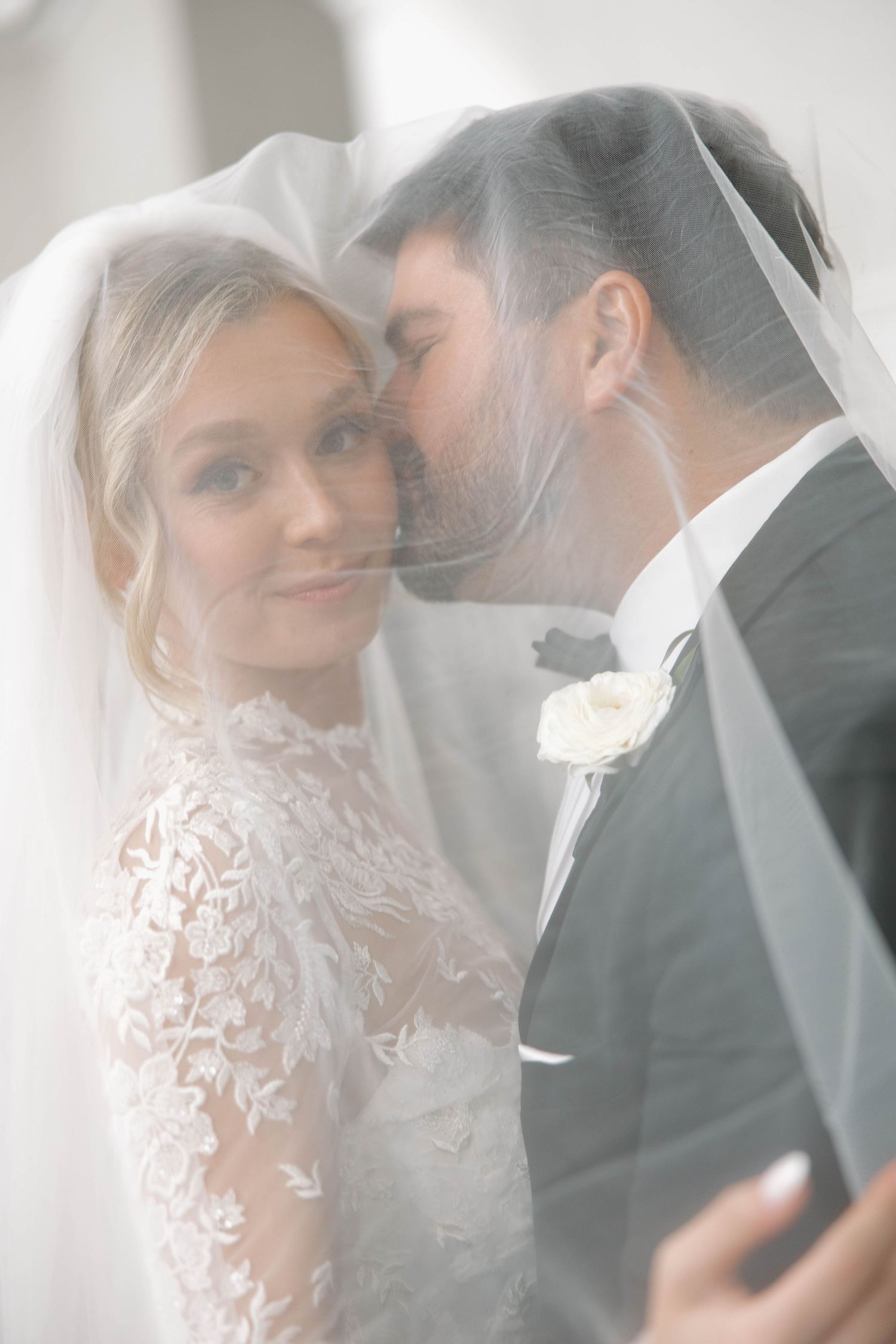 Artistic wedding portraits capturing tender moments through sheer bridal veil.