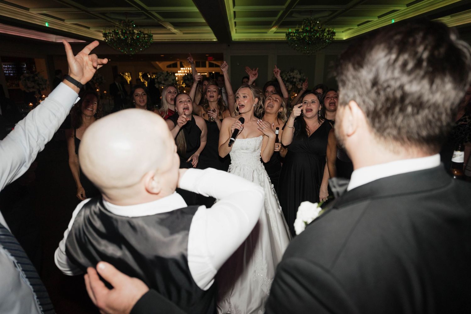Wedding reception dance floor packed with guests under dramatic venue lighting.
