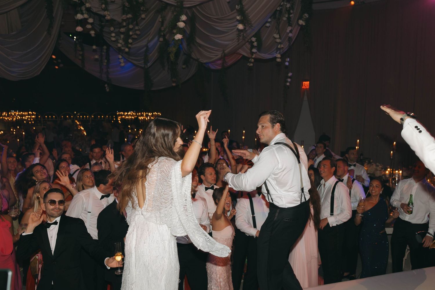 Lively dance floor scene with guests celebrating at nighttime wedding reception.