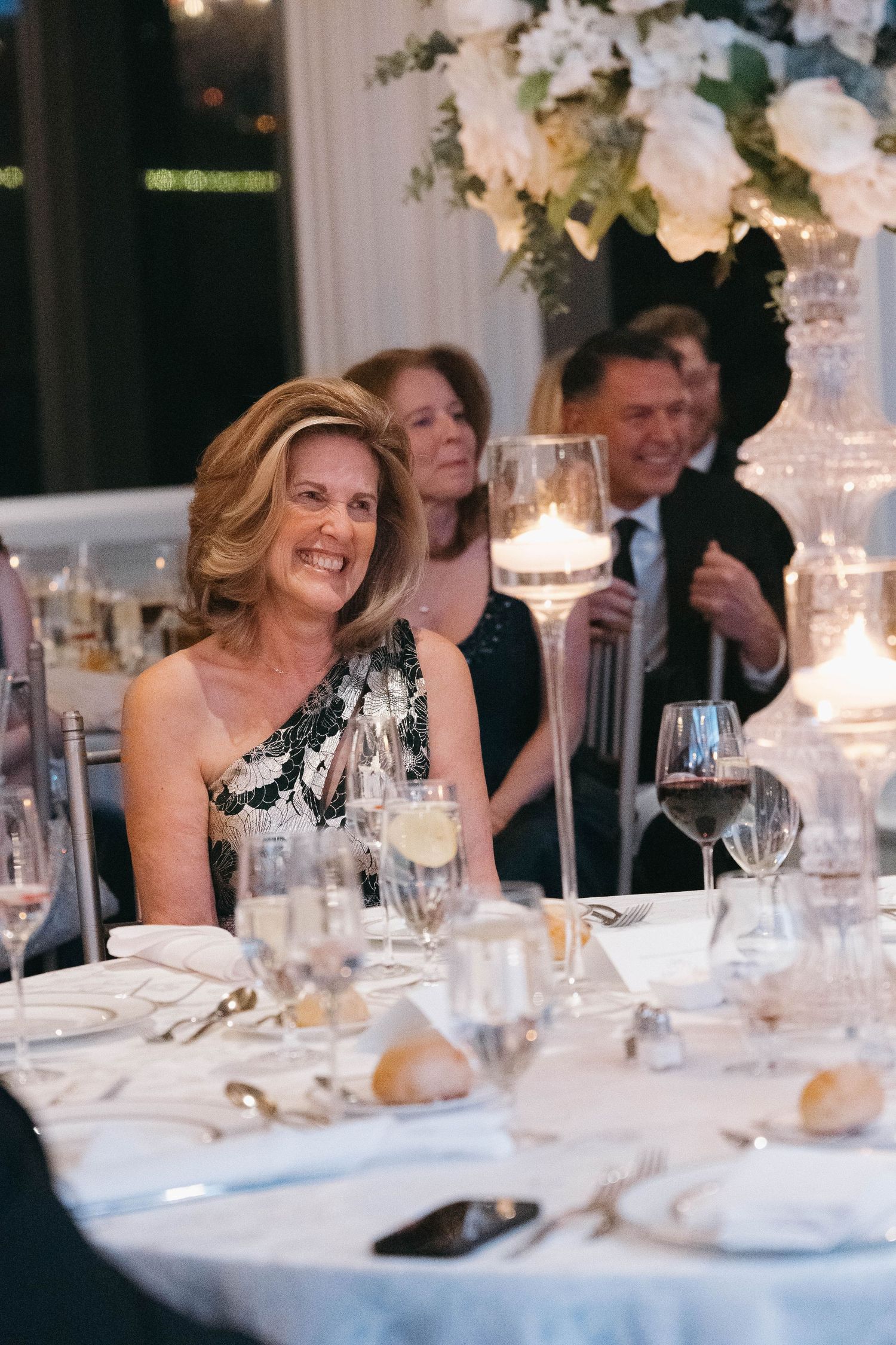 Guests enjoying conversation at an elegant wedding reception with white floral centerpieces.
