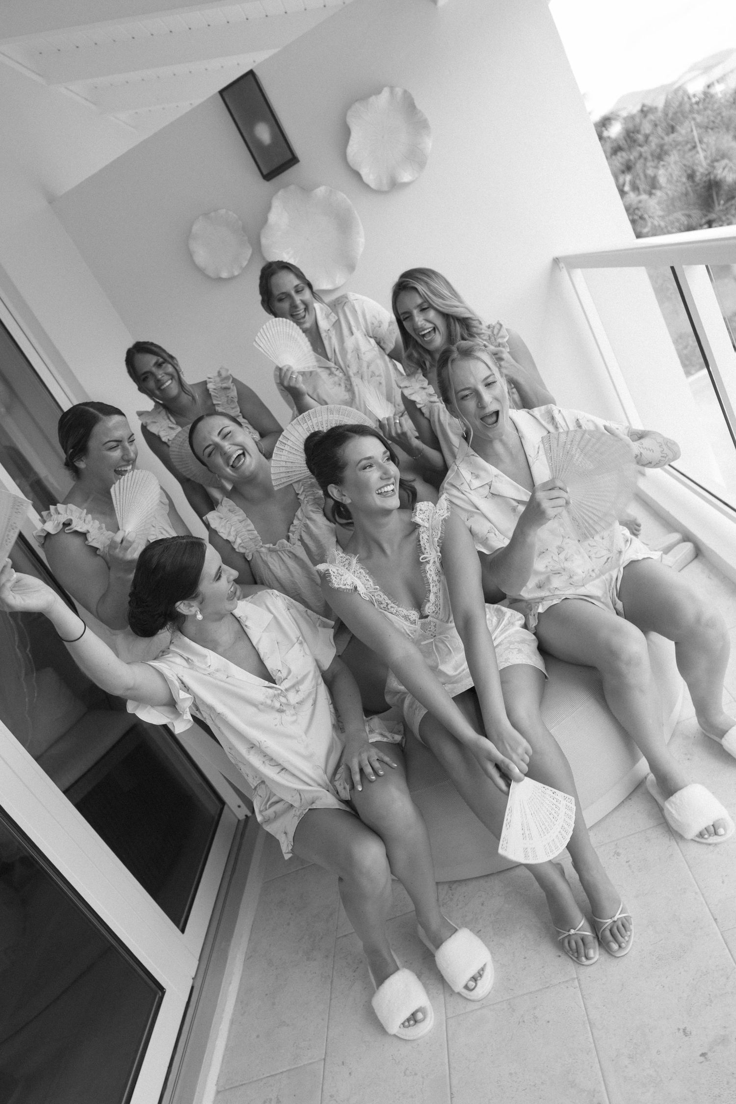 Bridal party laughing together in robes and slippers during getting ready preparations.