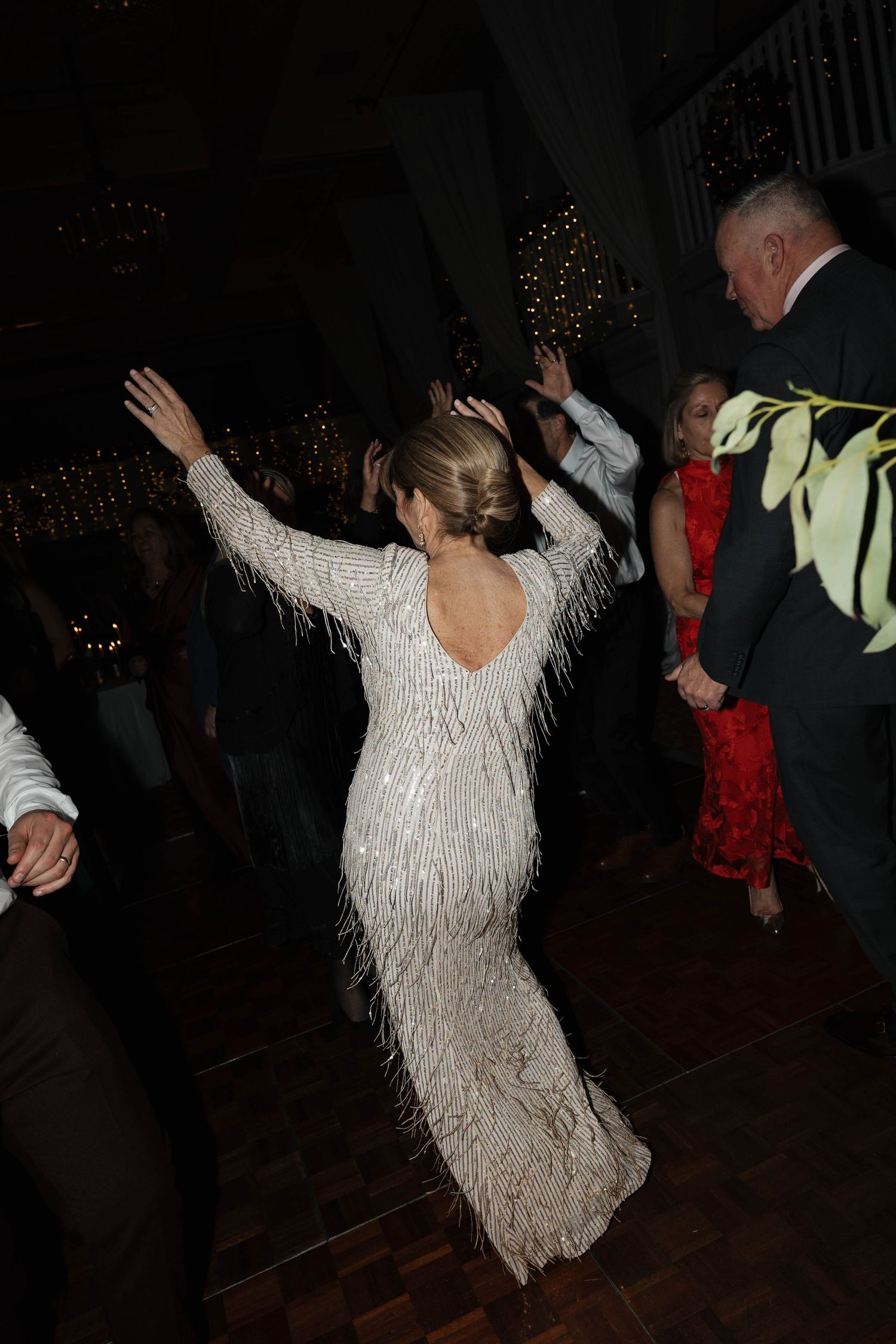 Wedding guests dancing energetically on a dark dance floor with a person in white dress spinning and twirling.