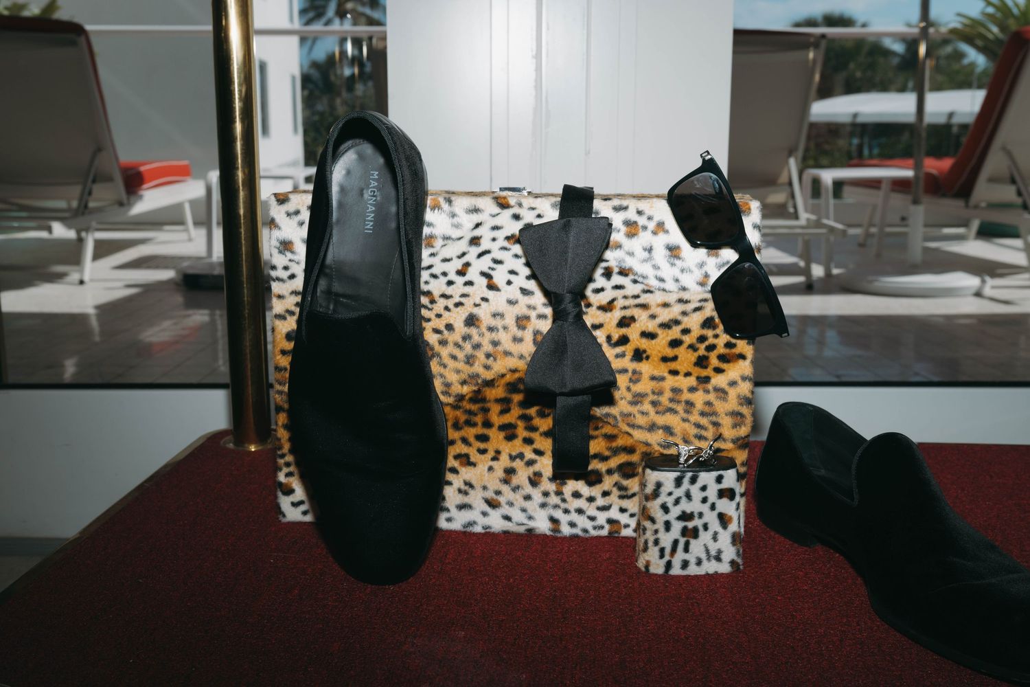 Leopard print boxes and black shoes arranged on a dark surface.