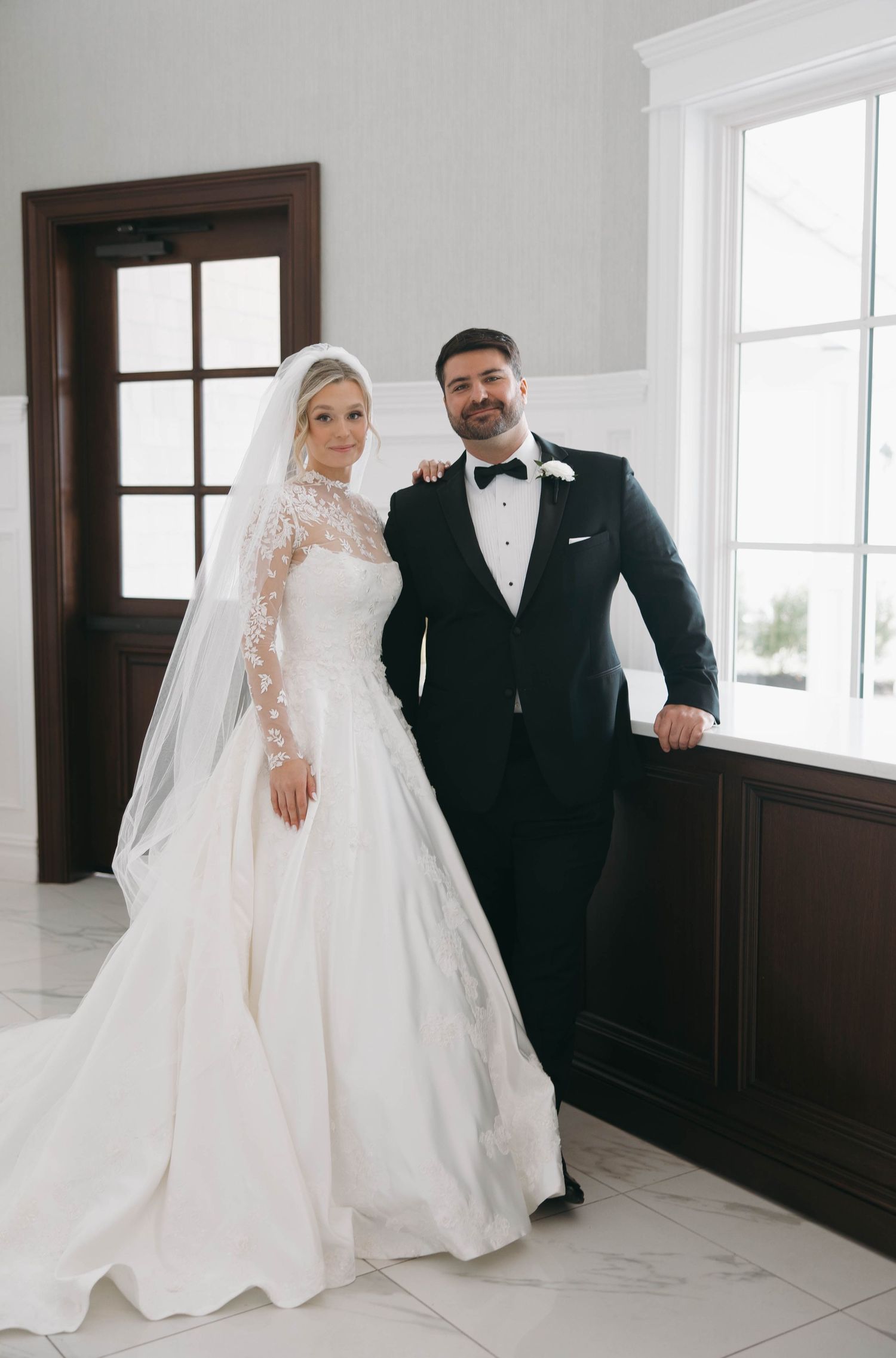 Elegant wedding portraits against white walls and dark wood paneling.