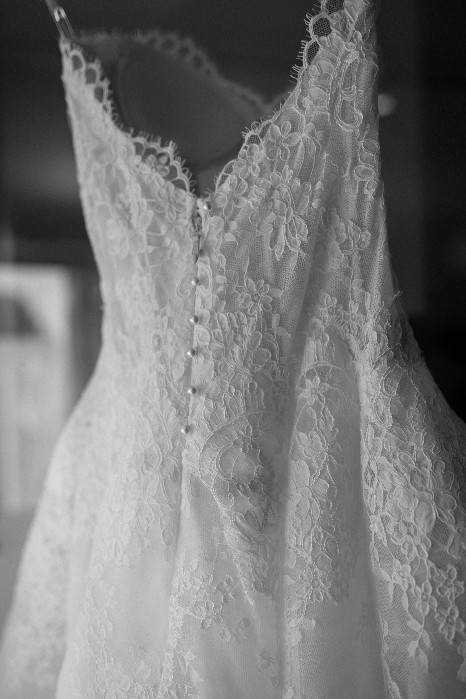 Close-up details of delicate white lace wedding dress patterns in black and white.