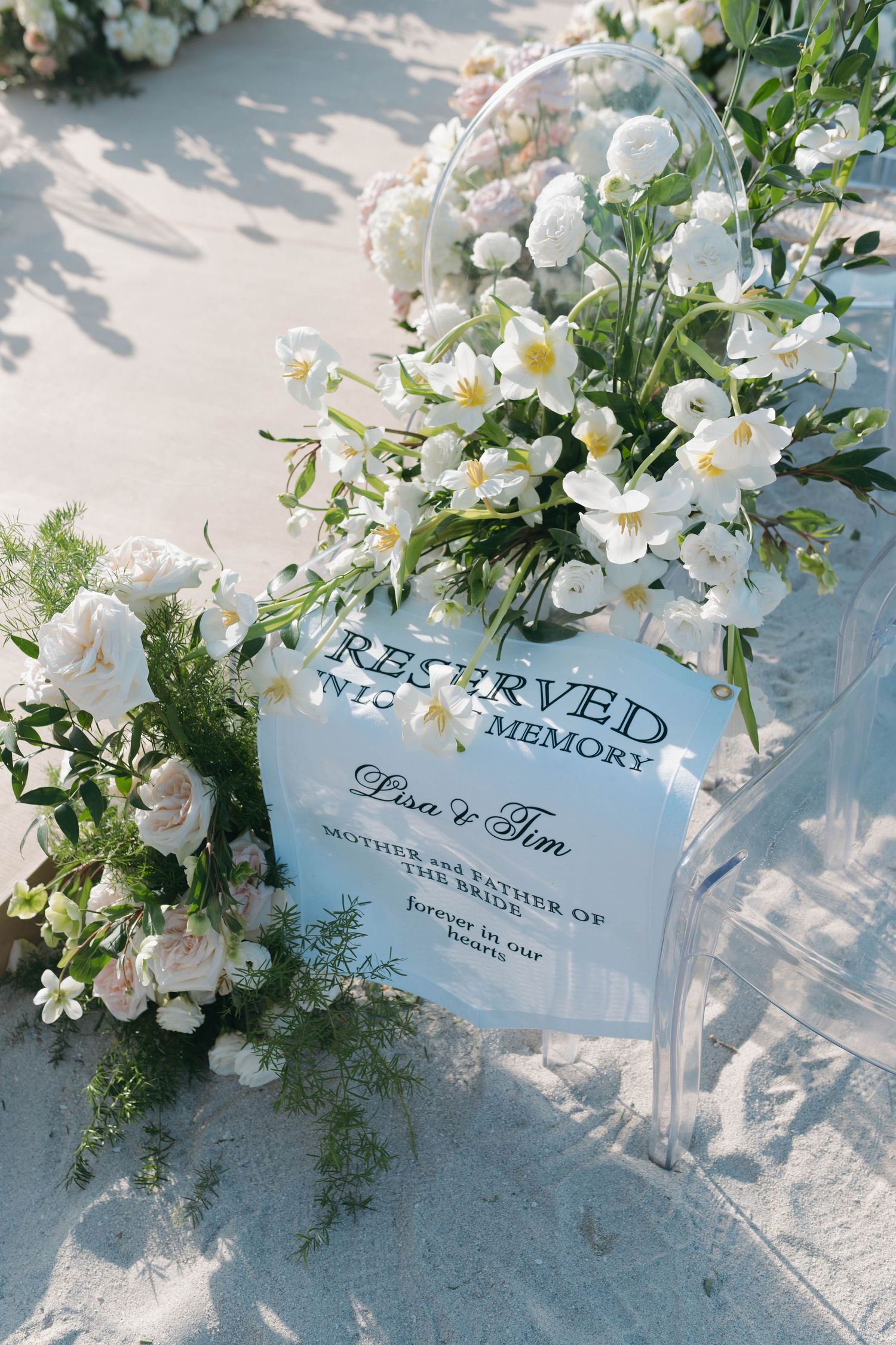 Elegant white floral arrangements with reserved seating cards displayed on a light surface.