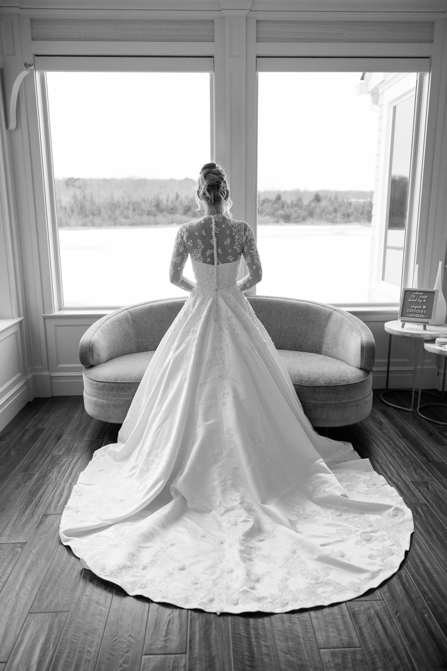 Elegant white wedding gown with dramatic full skirt and long train displayed on hardwood floor in natural light.