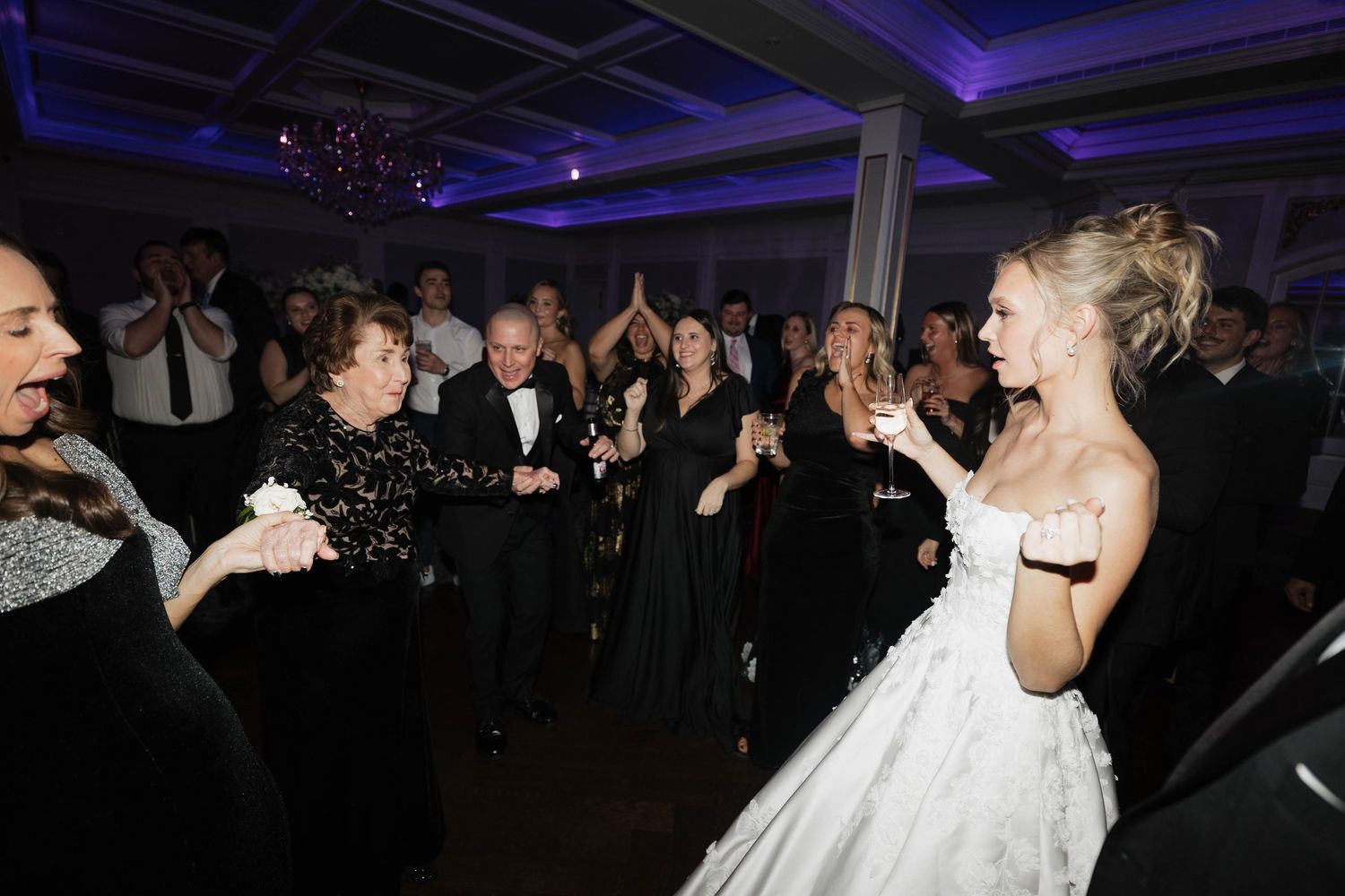 Wedding reception dance floor filled with guests under blue lighting.
