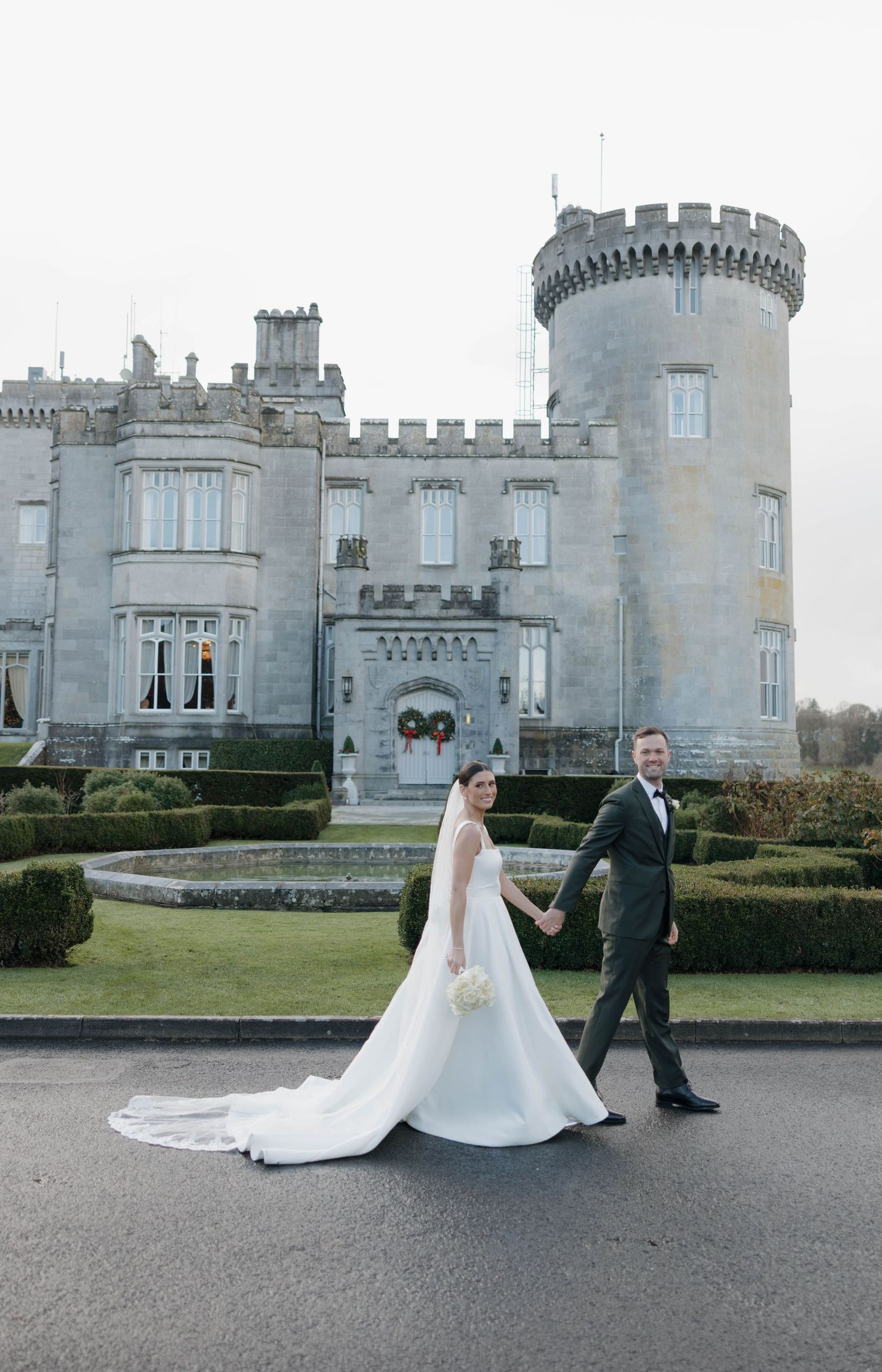 Elegant castle exterior with stone architecture and manicured hedges.