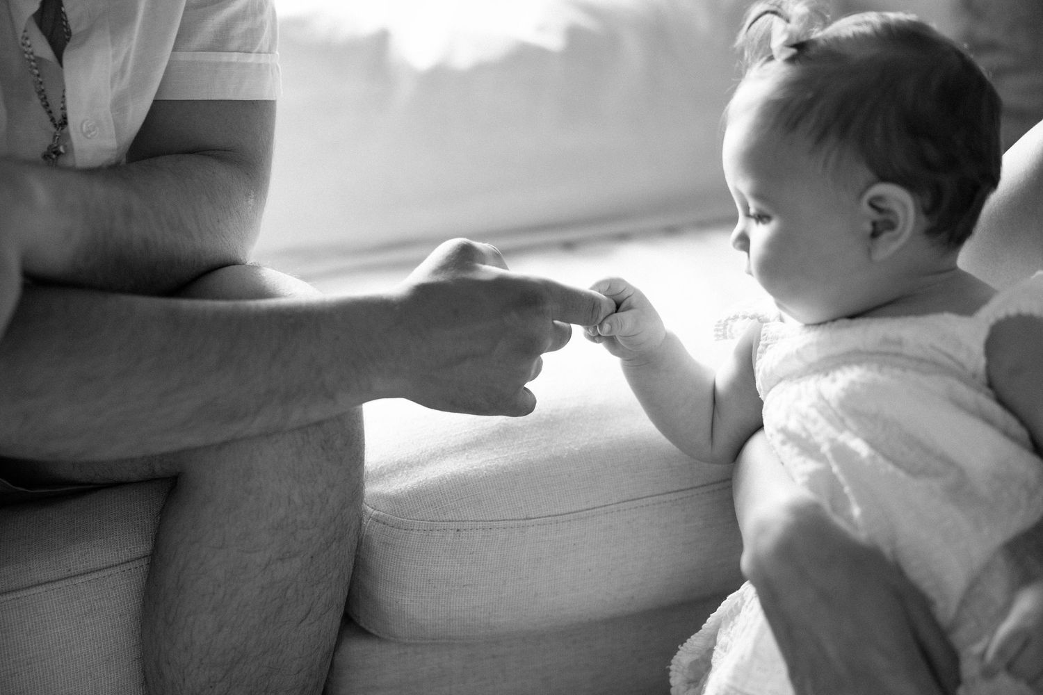 A black and white collage of candid moments showing a baby and parent interacting on a sofa.
