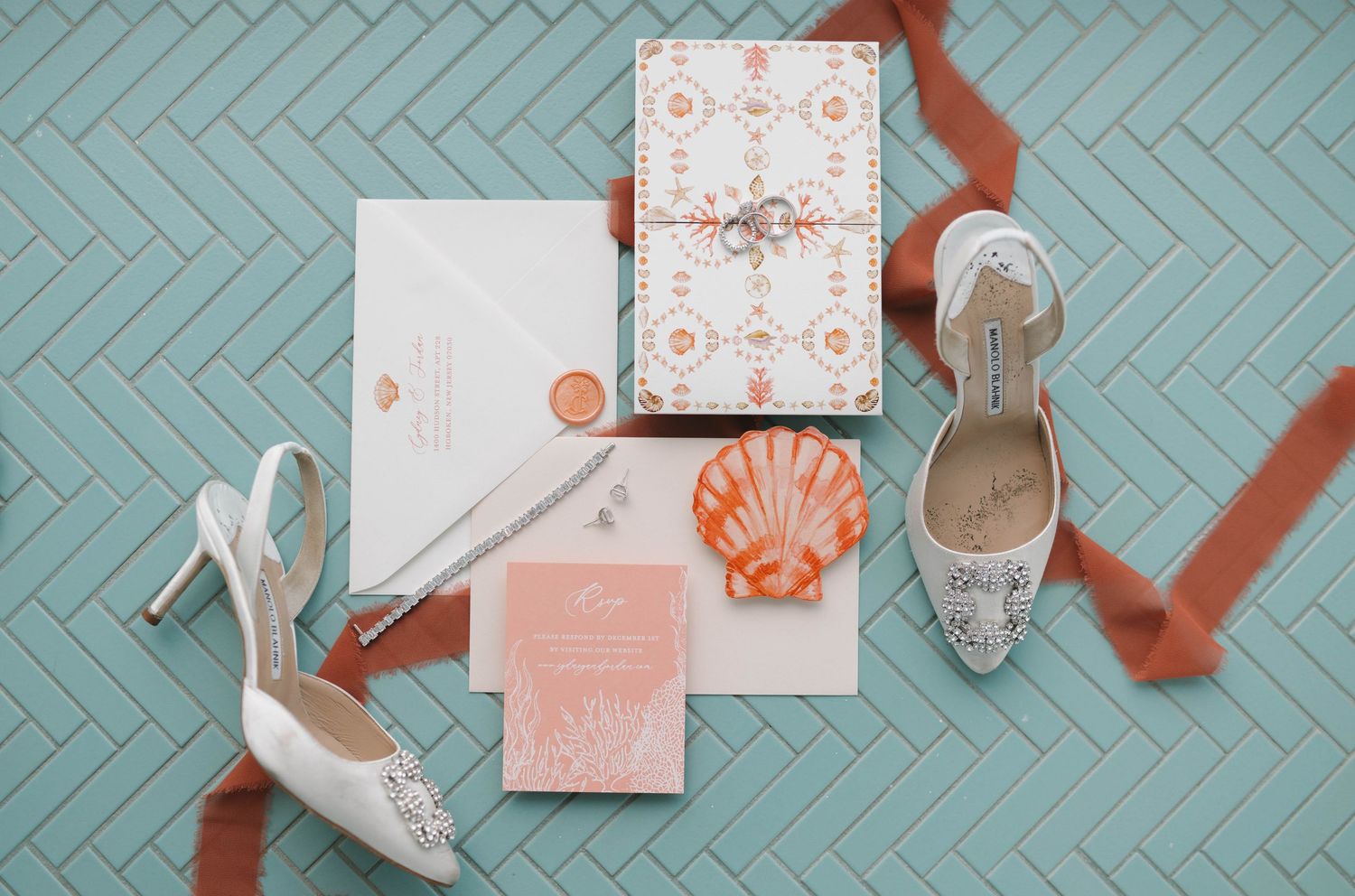 Beach themed wedding stationery with seashell motifs and silver shoes on turquoise background.