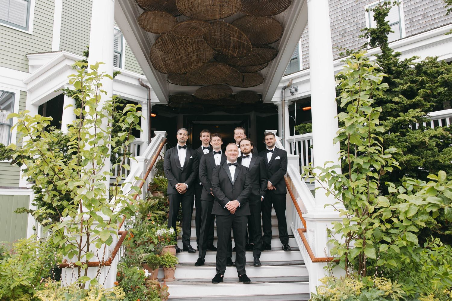 Wedding party members gather on the elegant white porch of a classic Nantucket hotel.