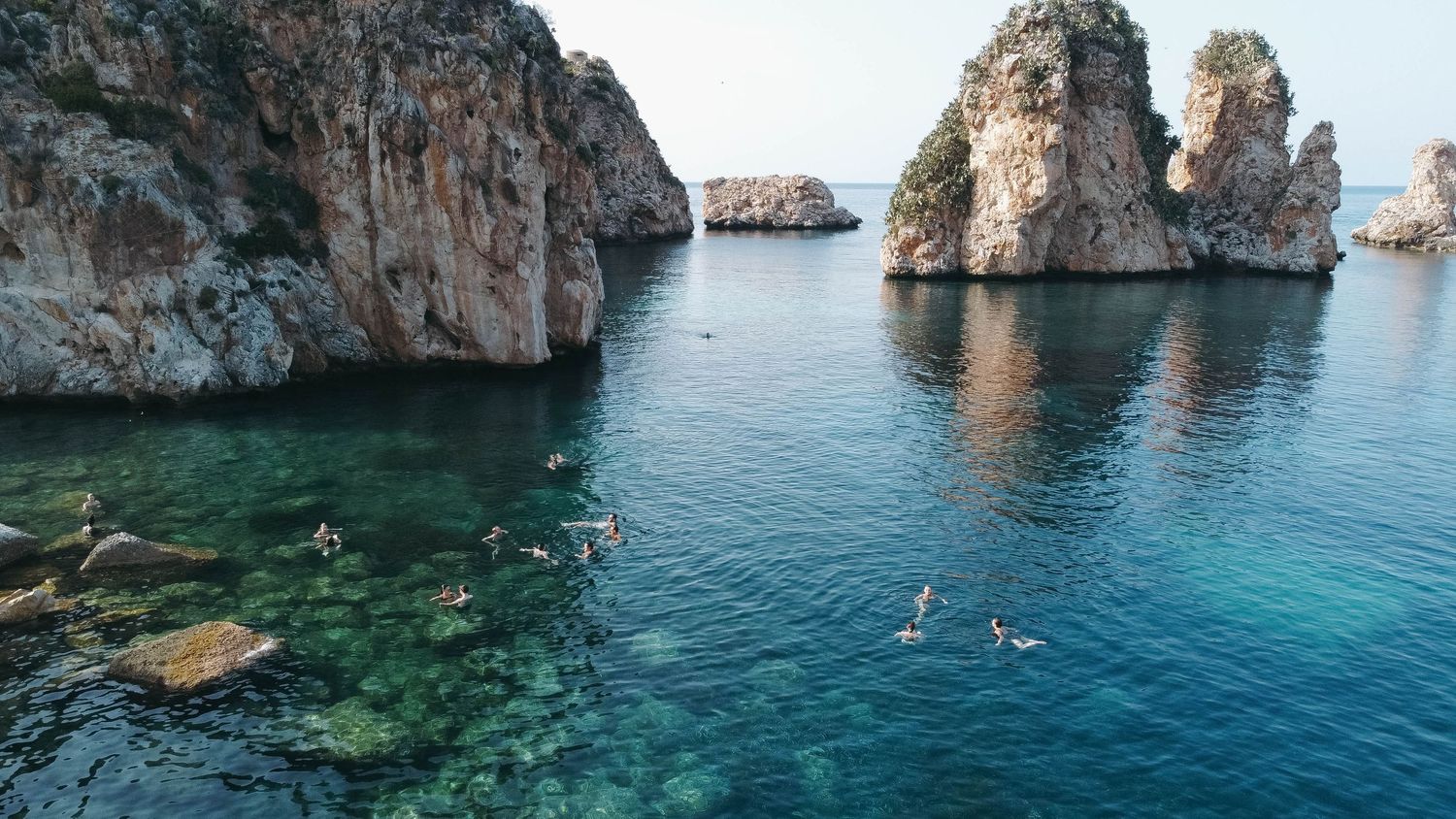 Scenic panorama of rugged coastline with turquoise waters and rocky outcrops in Mediterranean setting.