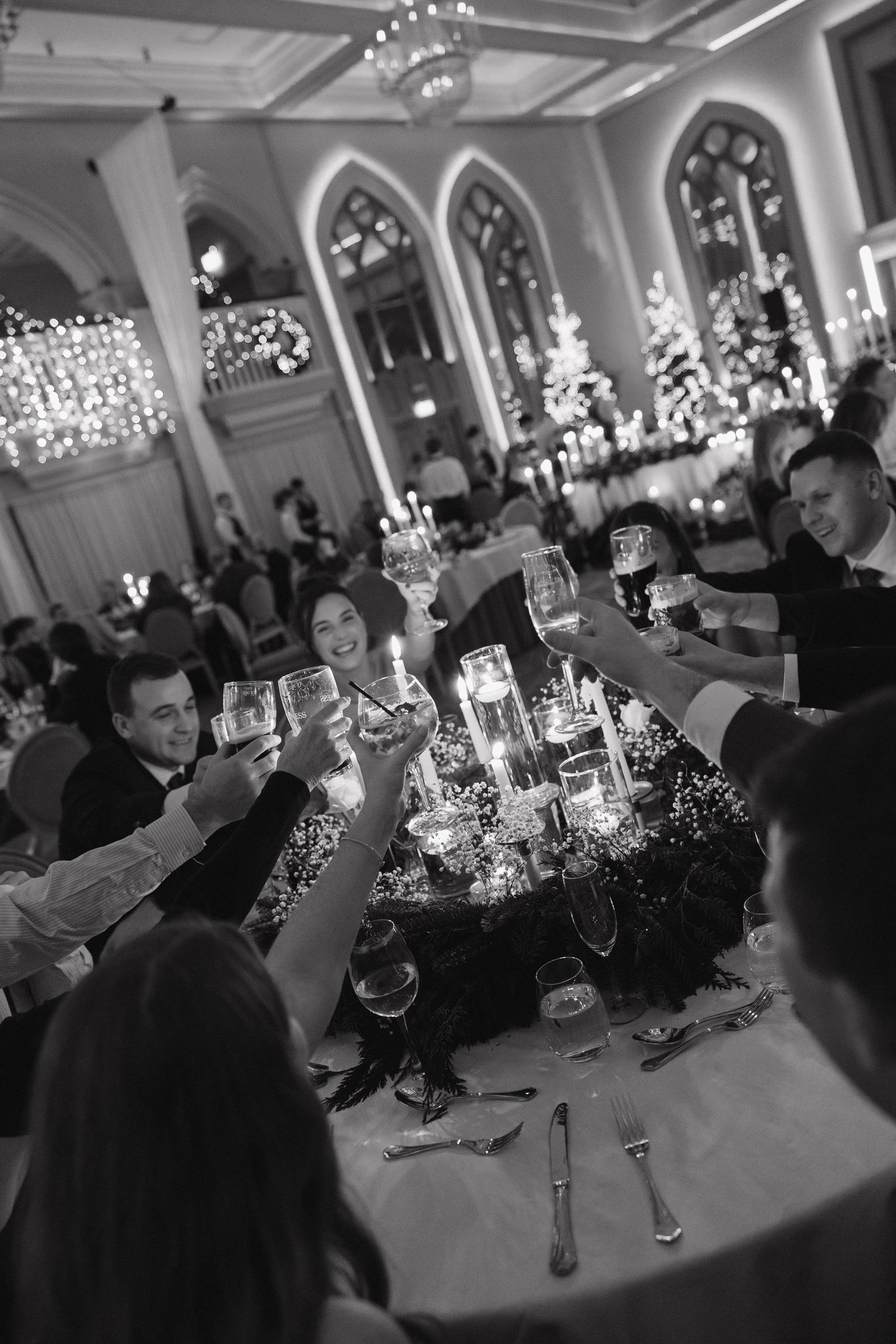 Wedding guests raise their glasses in a toast during an elegant evening reception.