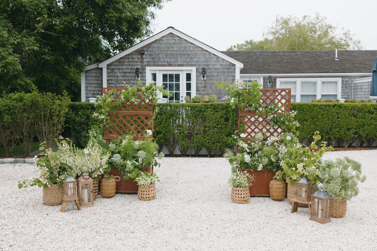 Beachside wedding venue setup with gray shingled houses and decorative floral arrangements.