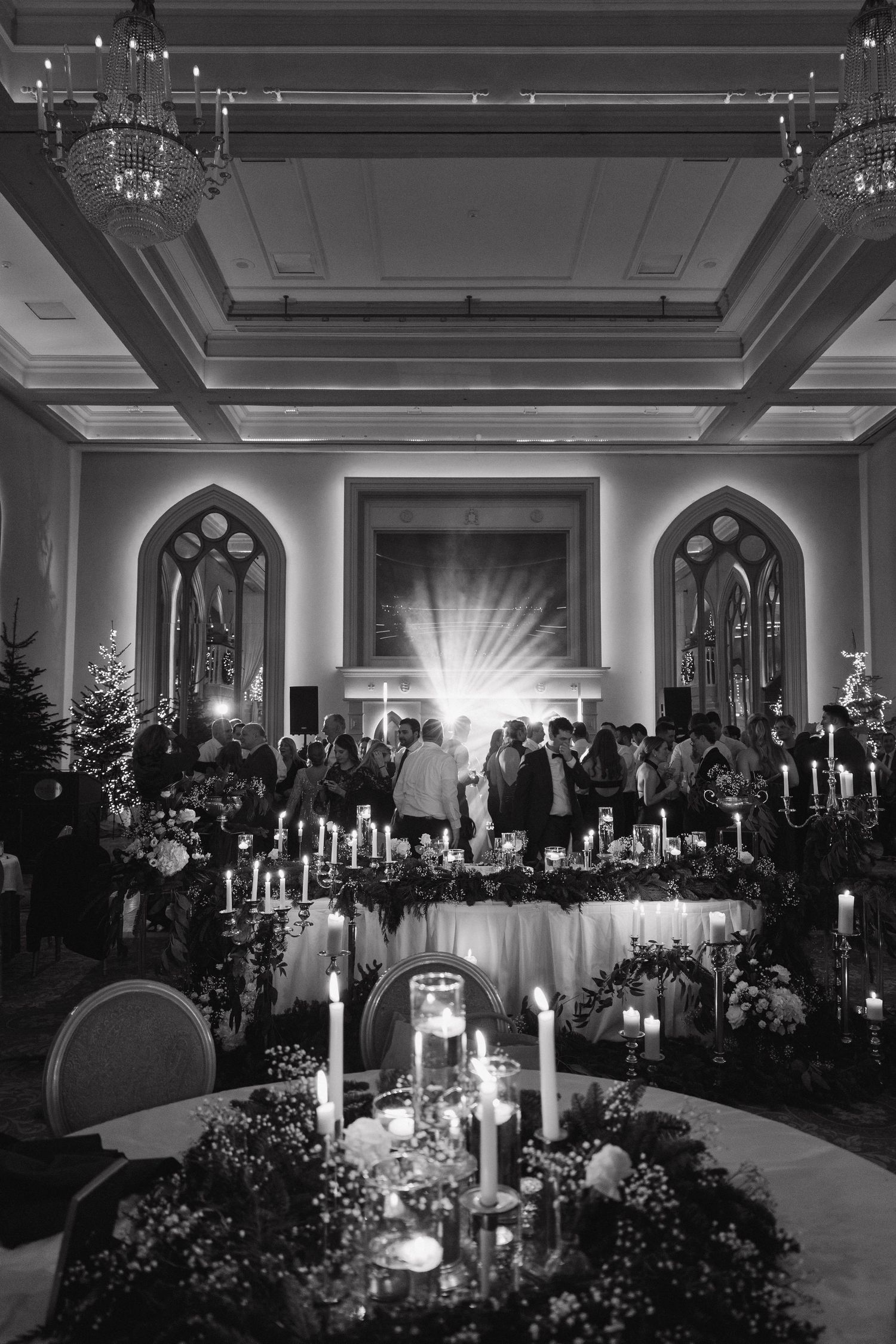 Elegant wedding reception hall decorated with candles and floral arrangements in dramatic lighting.