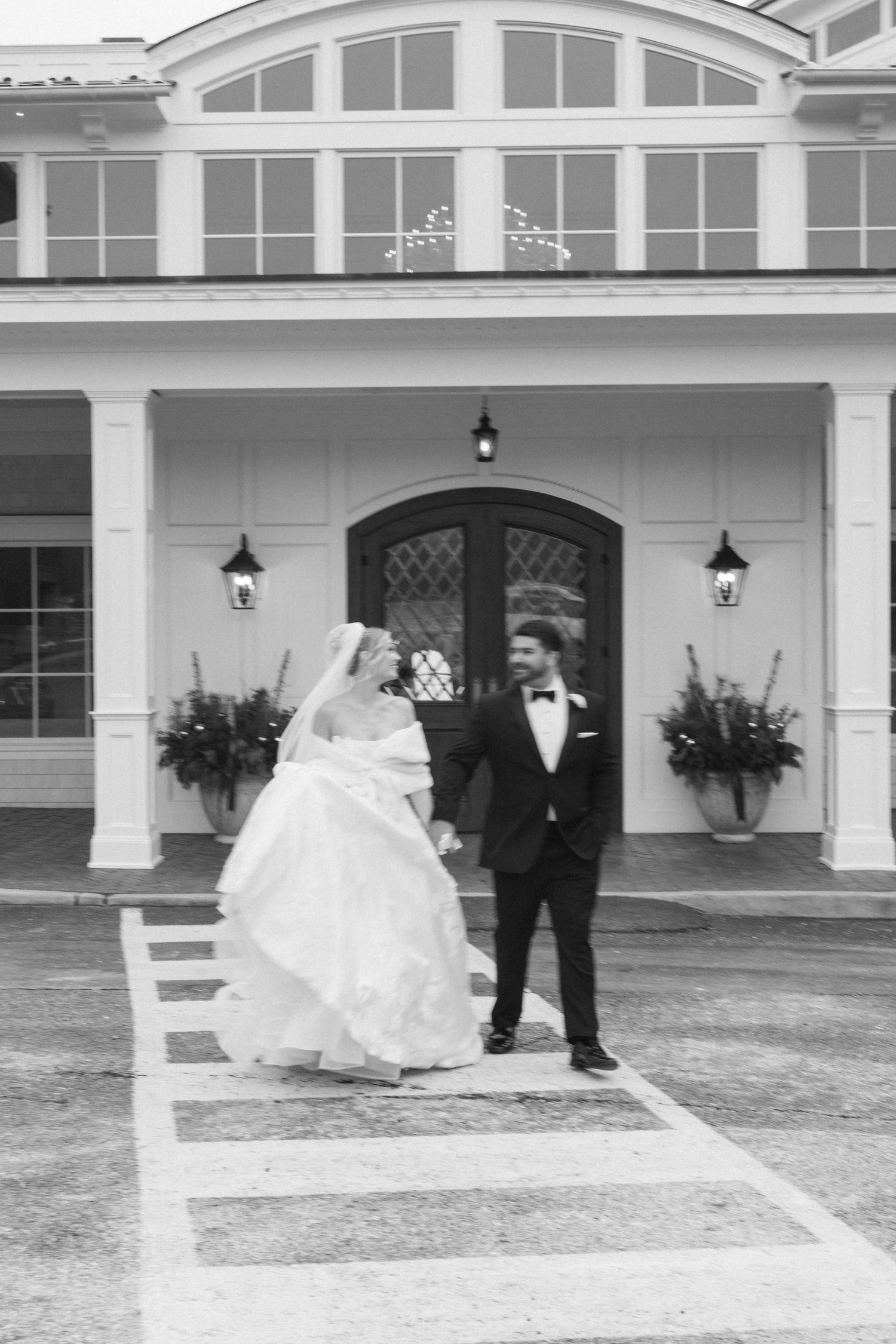 A flowing white wedding dress twirls gracefully against a white colonial-style building backdrop.