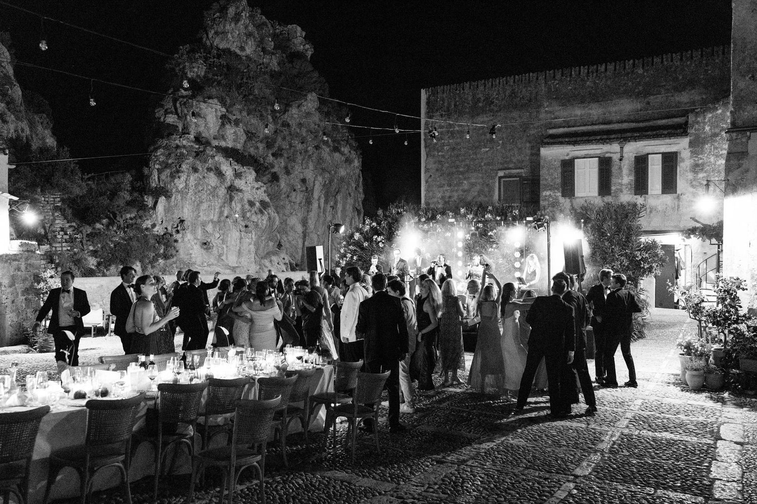 Black and white capture of a nighttime reception with guests gathered in a historic venue.