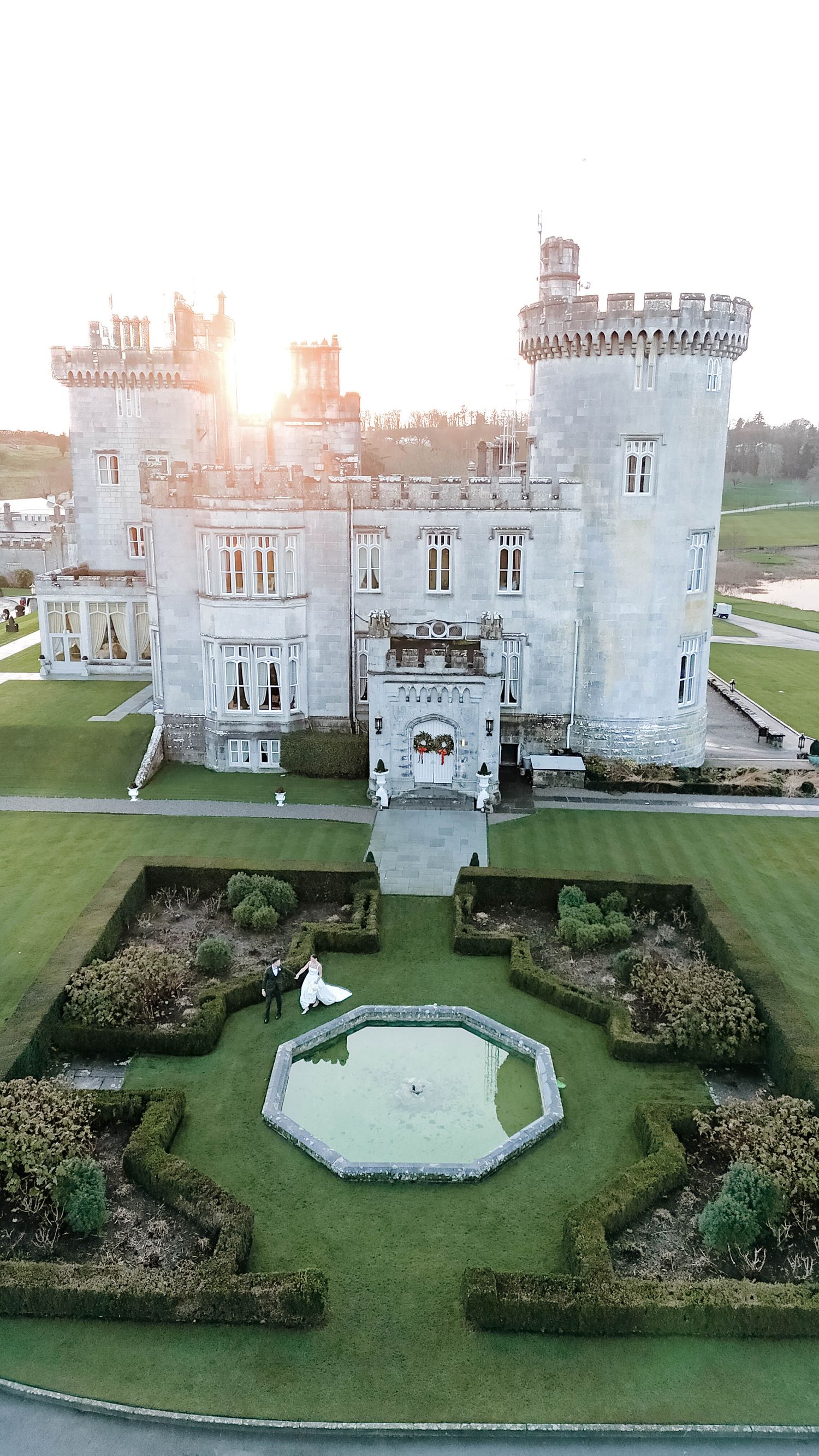 Stone castle with ornate towers and formal gardens featuring a symmetrical layout and water feature.