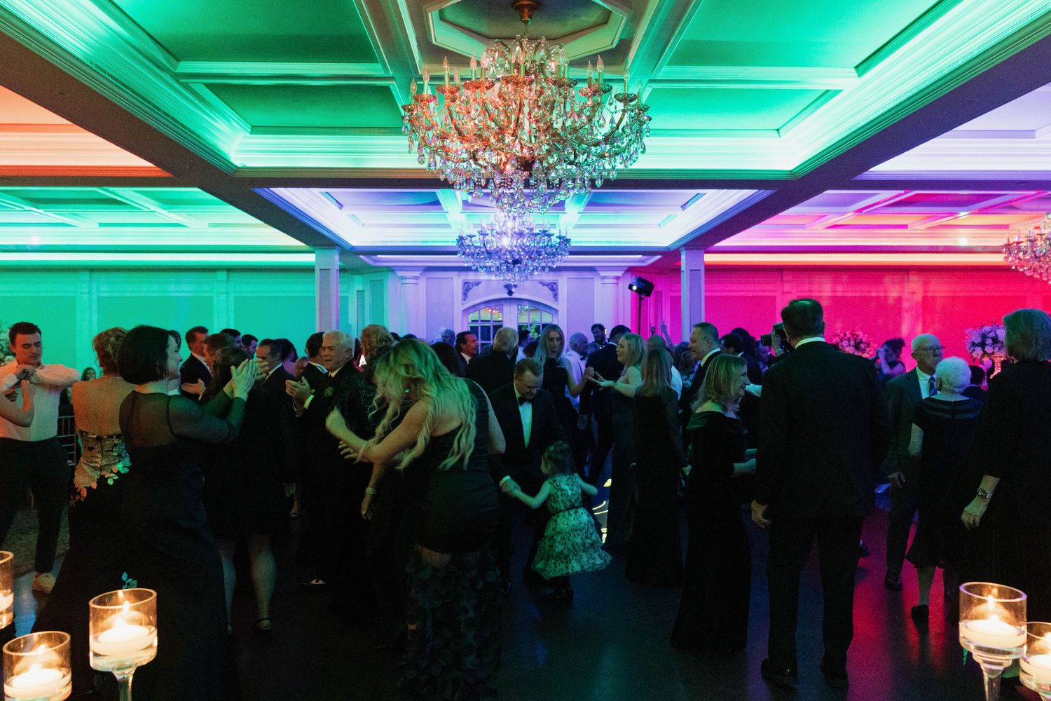 Ballroom venue with dramatic green and purple uplighting creating a festive atmosphere.