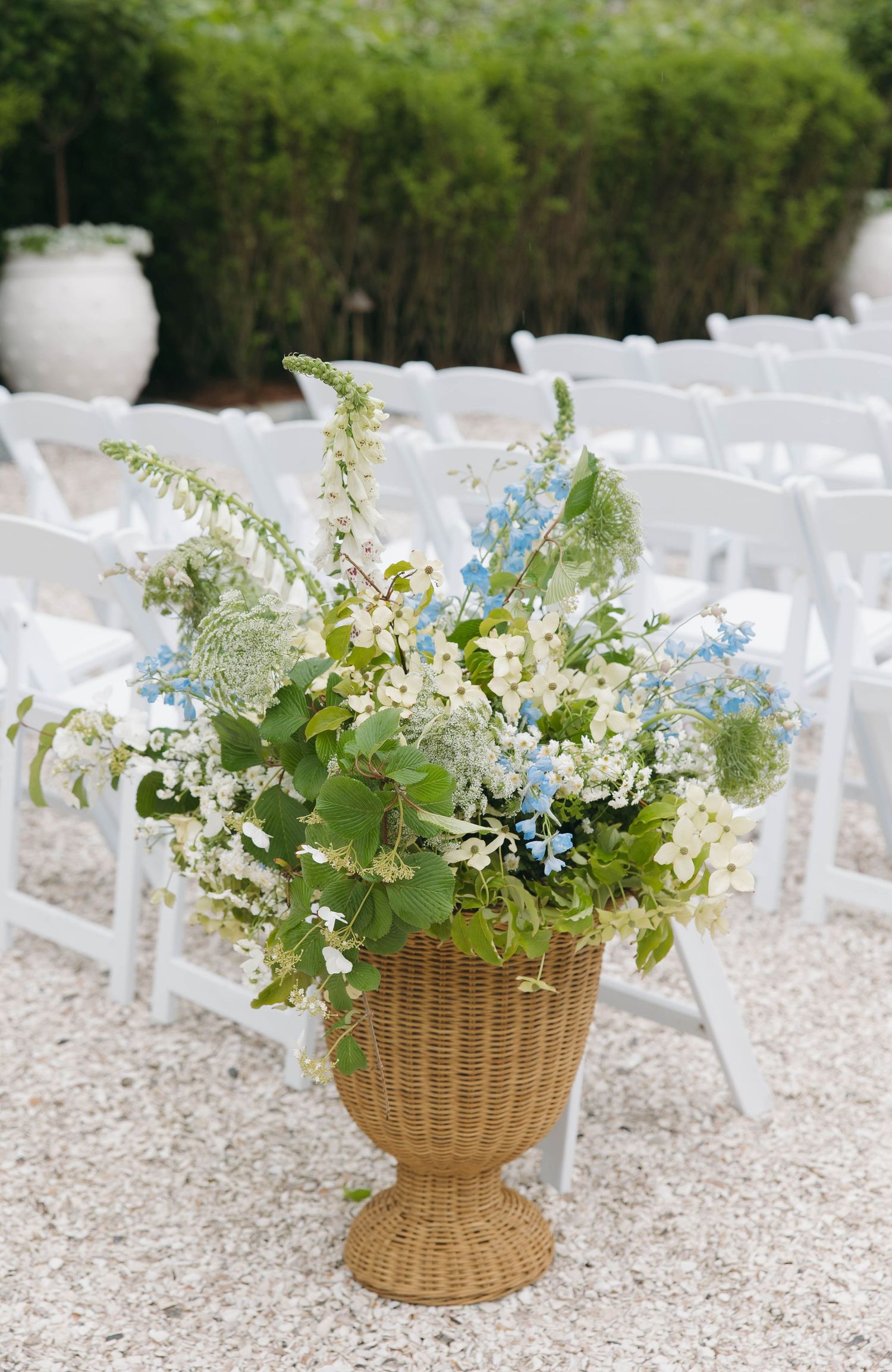 White wicker baskets filled with delicate blue and white wildflowers decorate outdoor ceremony space.
